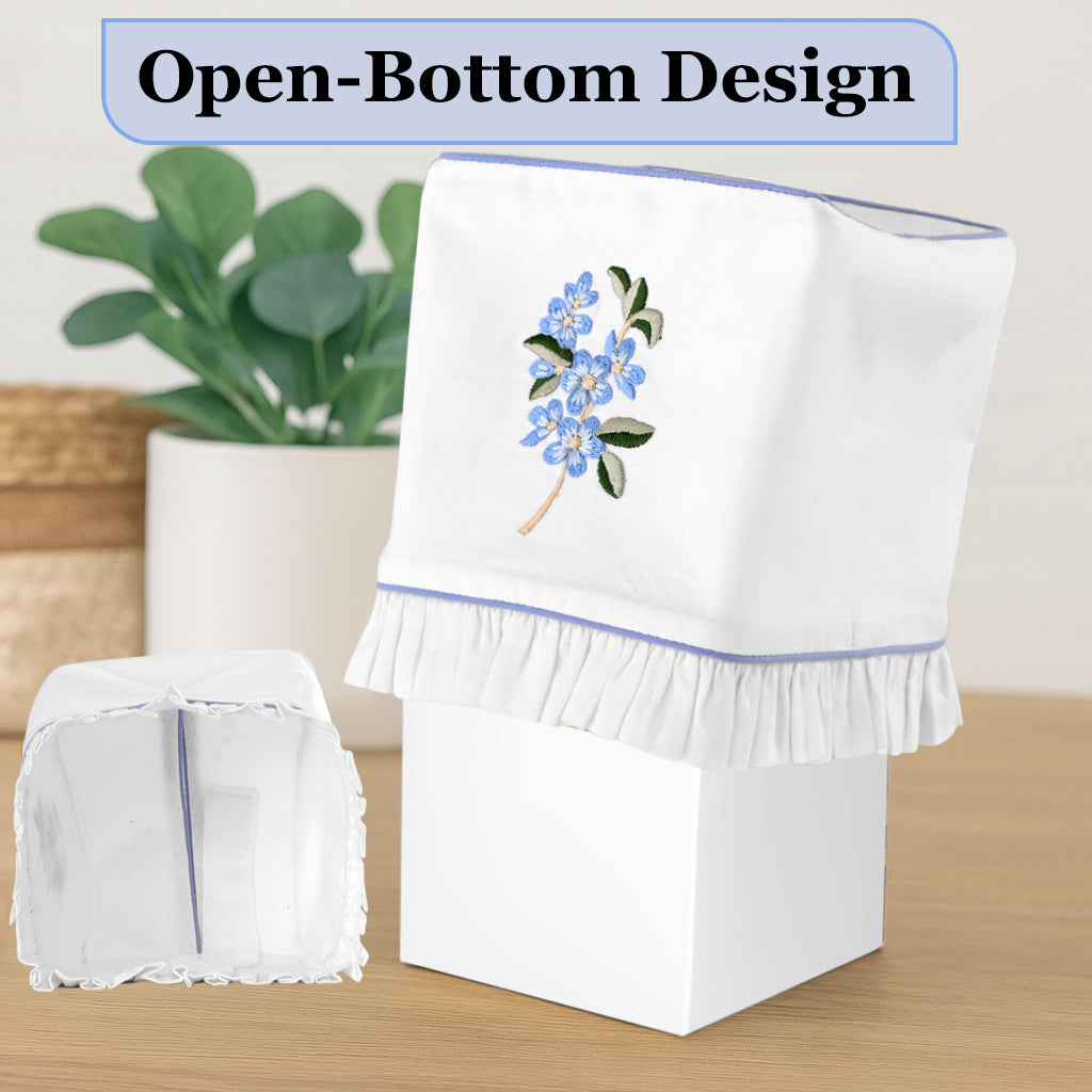 White towel with floral design on a wooden surface with a plant in the background