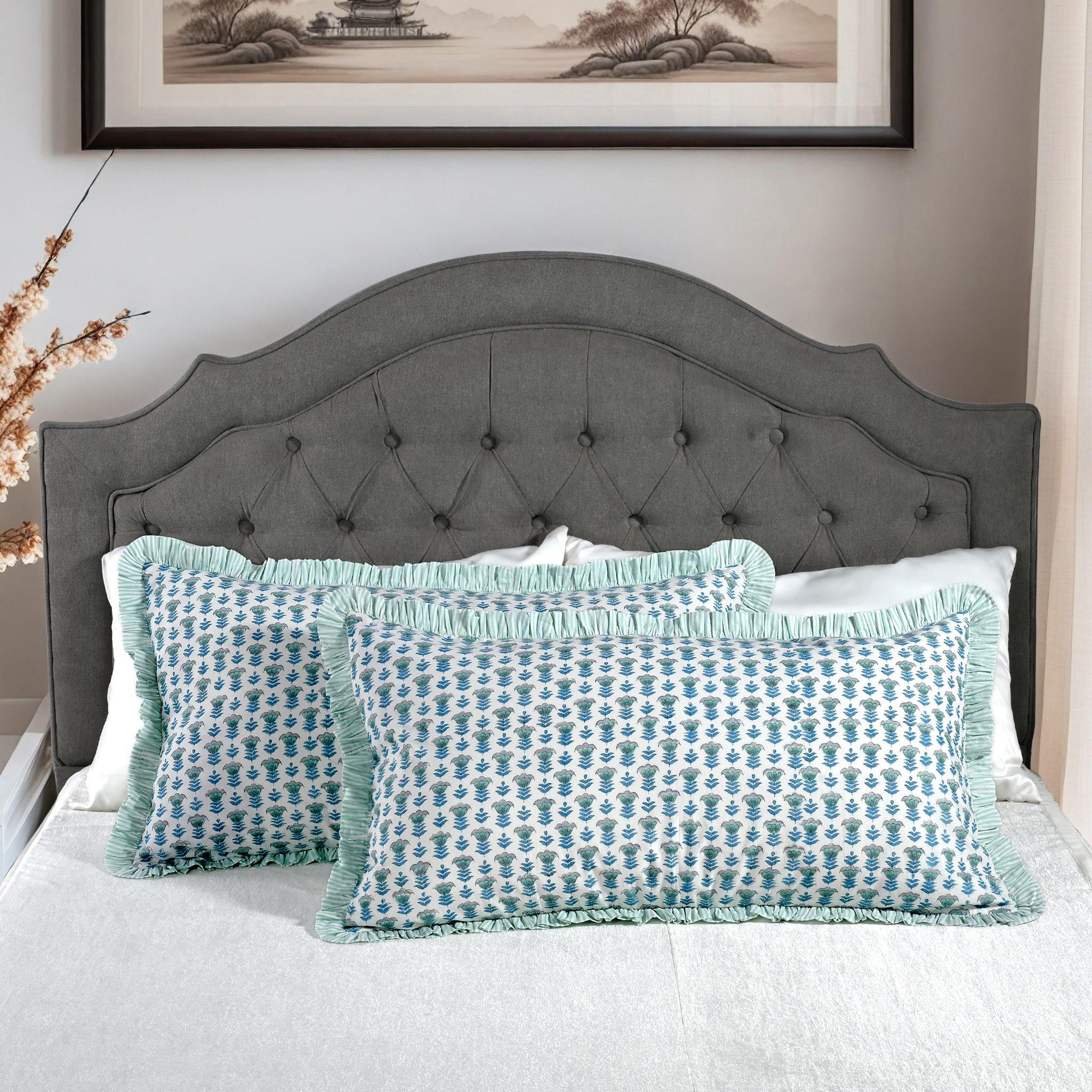 Large block print cotton pillows styled on gray upholstered bed.