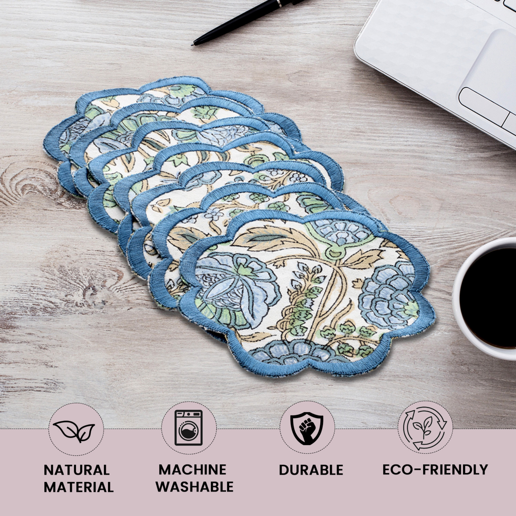 Set of floral coasters on a wooden surface with coffee and laptop.