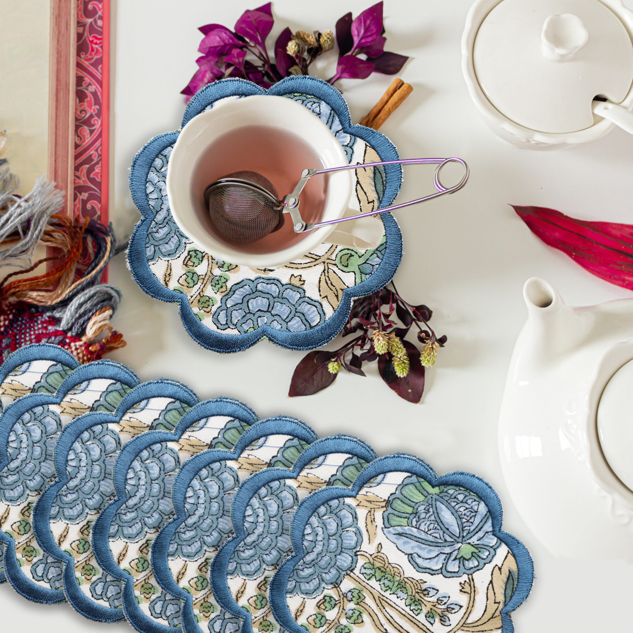 Set of decorative coasters with a floral design on a table with tea accessories.