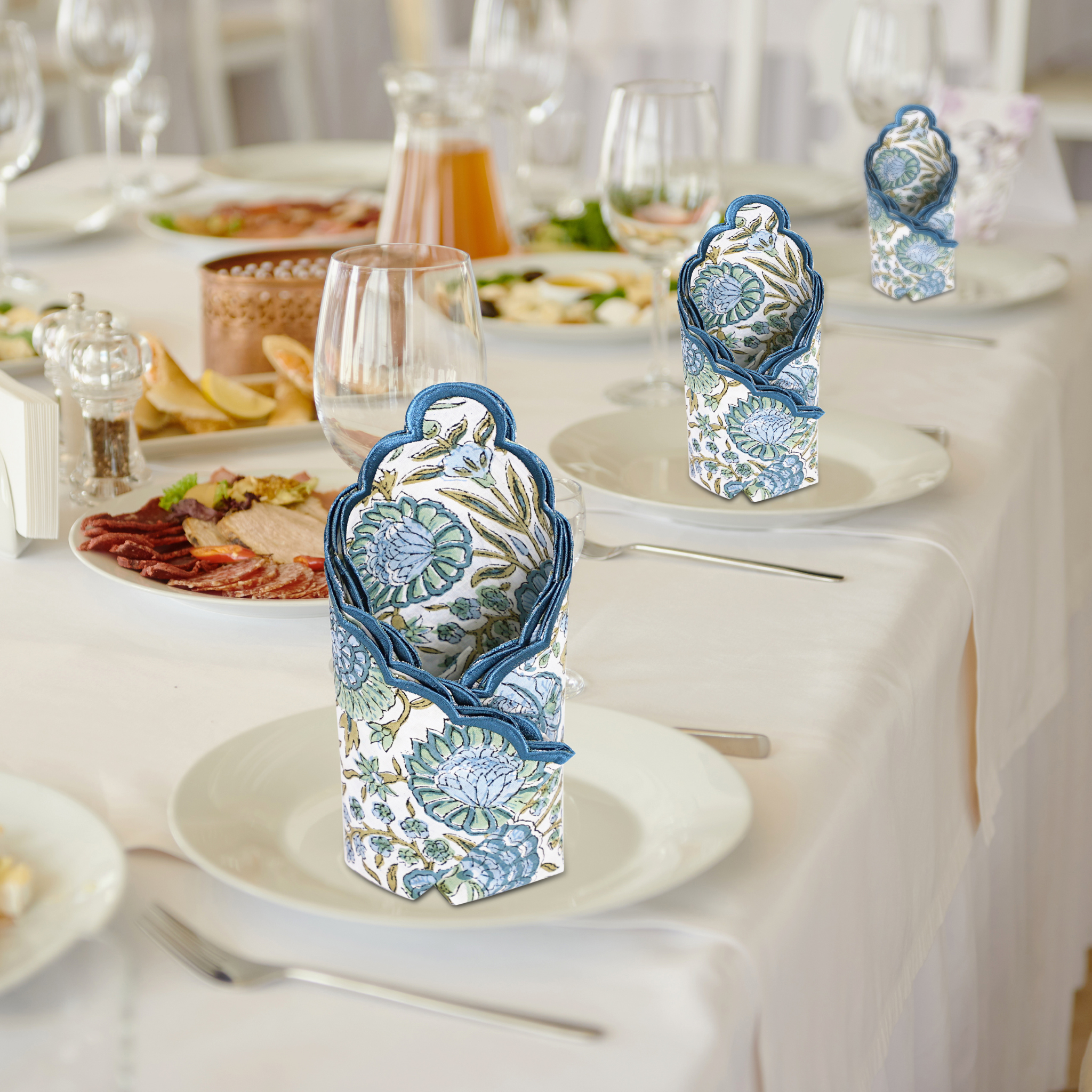 Decorative blue and white napkin holders on a set dining table with plates and glasses.