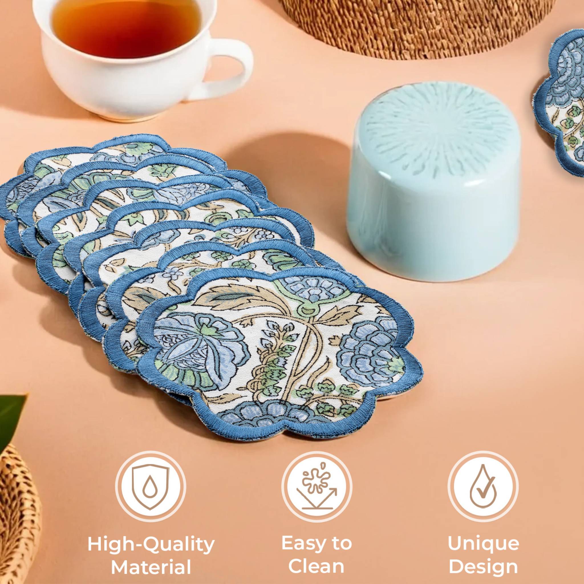 Set of floral coasters with a cup of tea and a container on a beige surface.