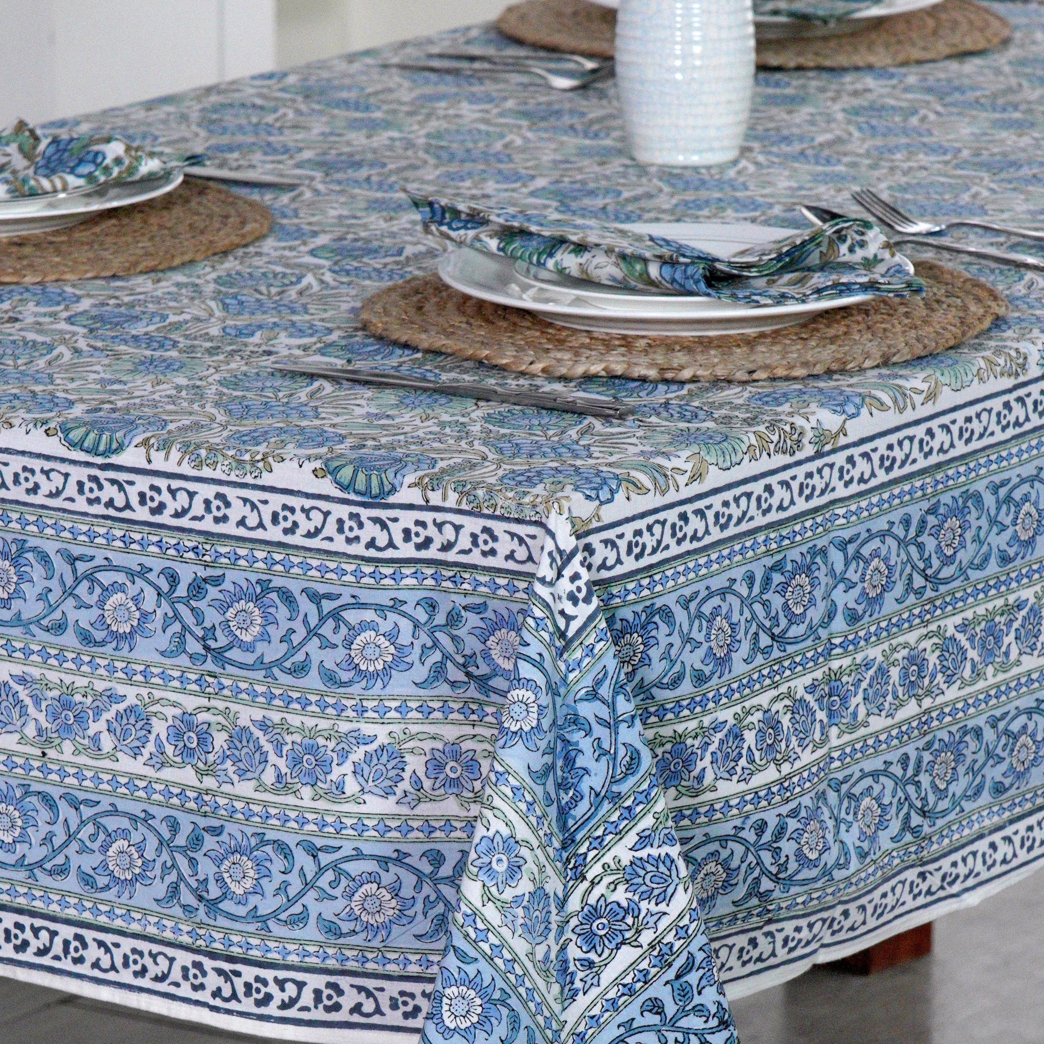 Table setting with a blue patterned tablecloth on a wooden table.