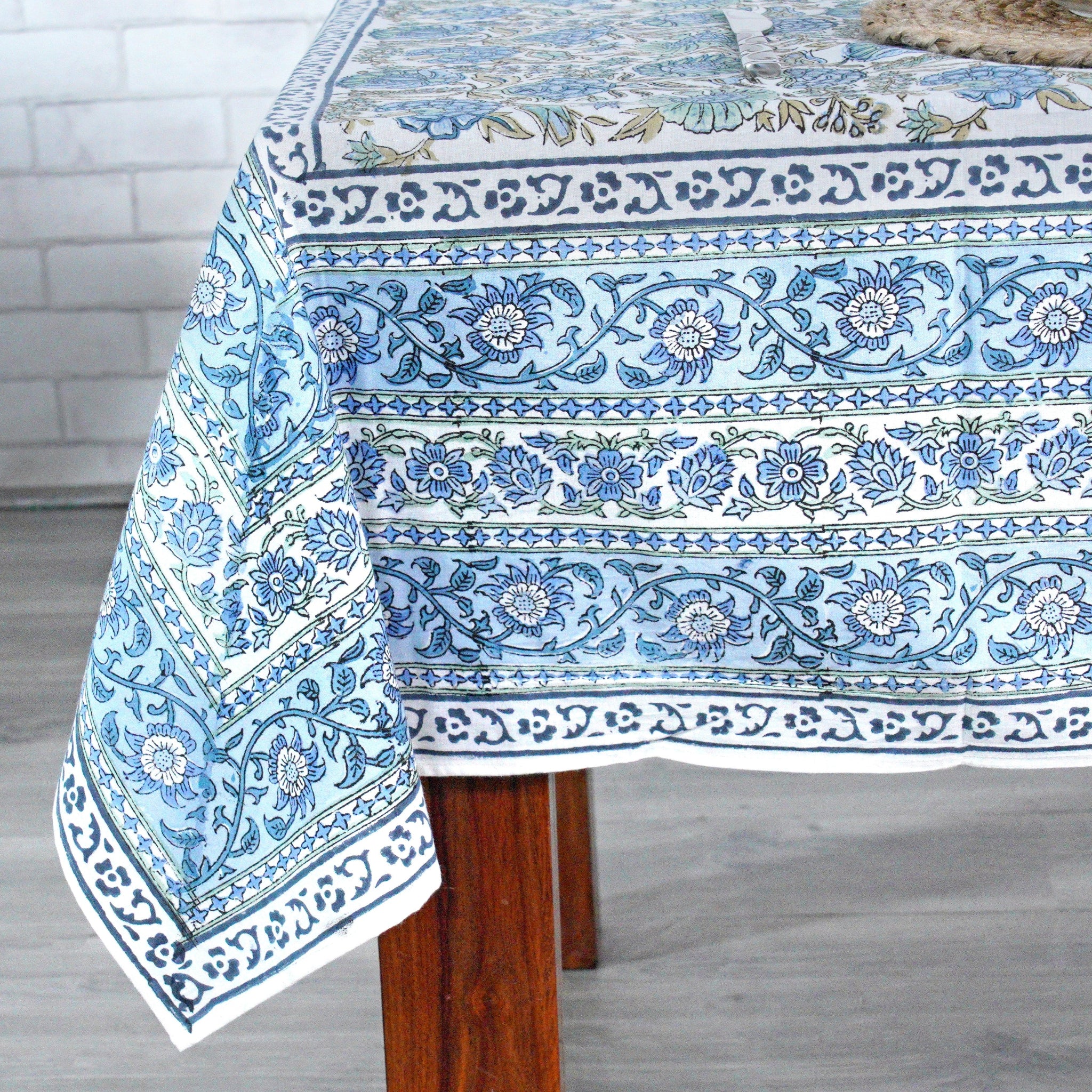 Blue and white patterned tablecloth on a wooden table with a light gray background