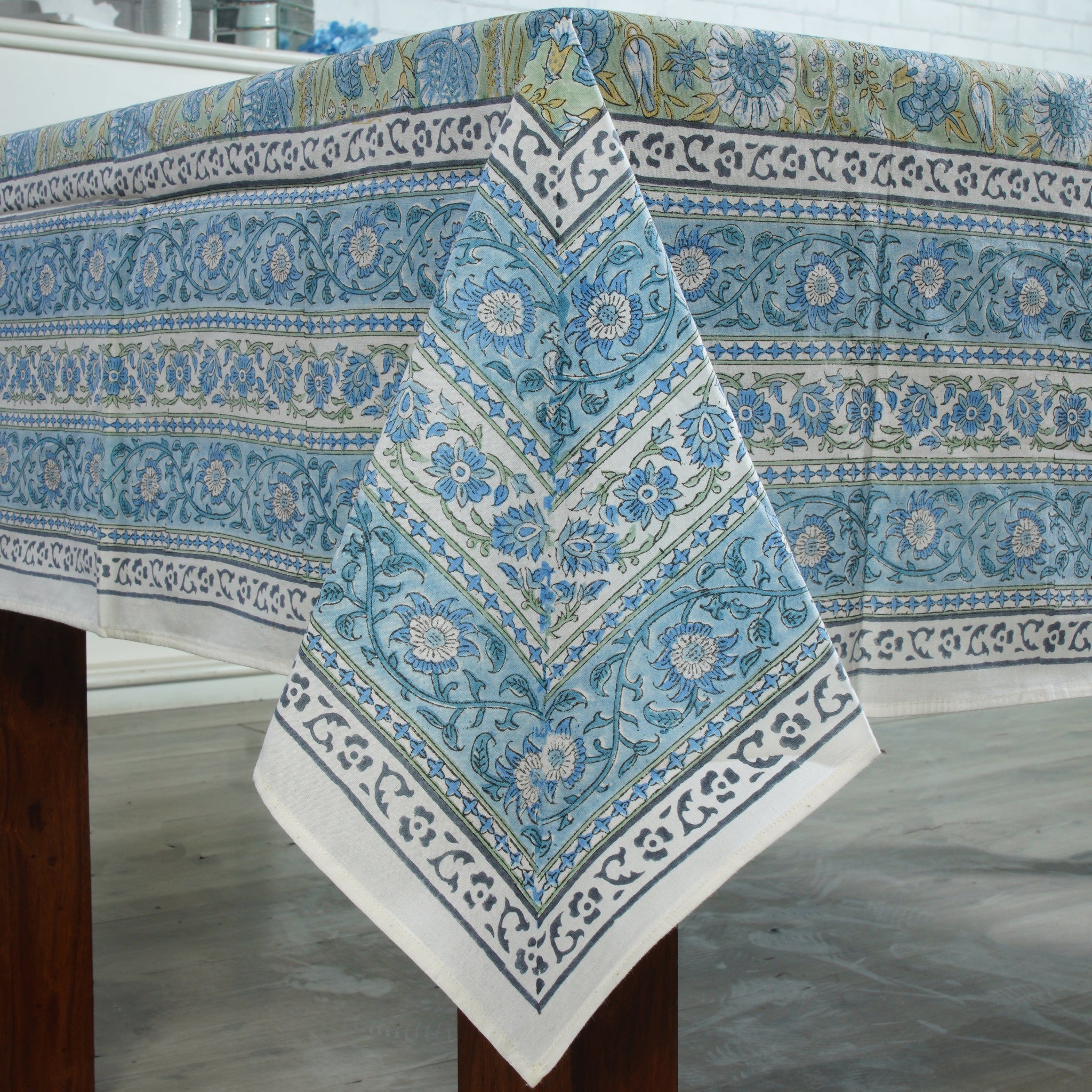 Decorative tablecloth with blue and white floral pattern on a wooden table.