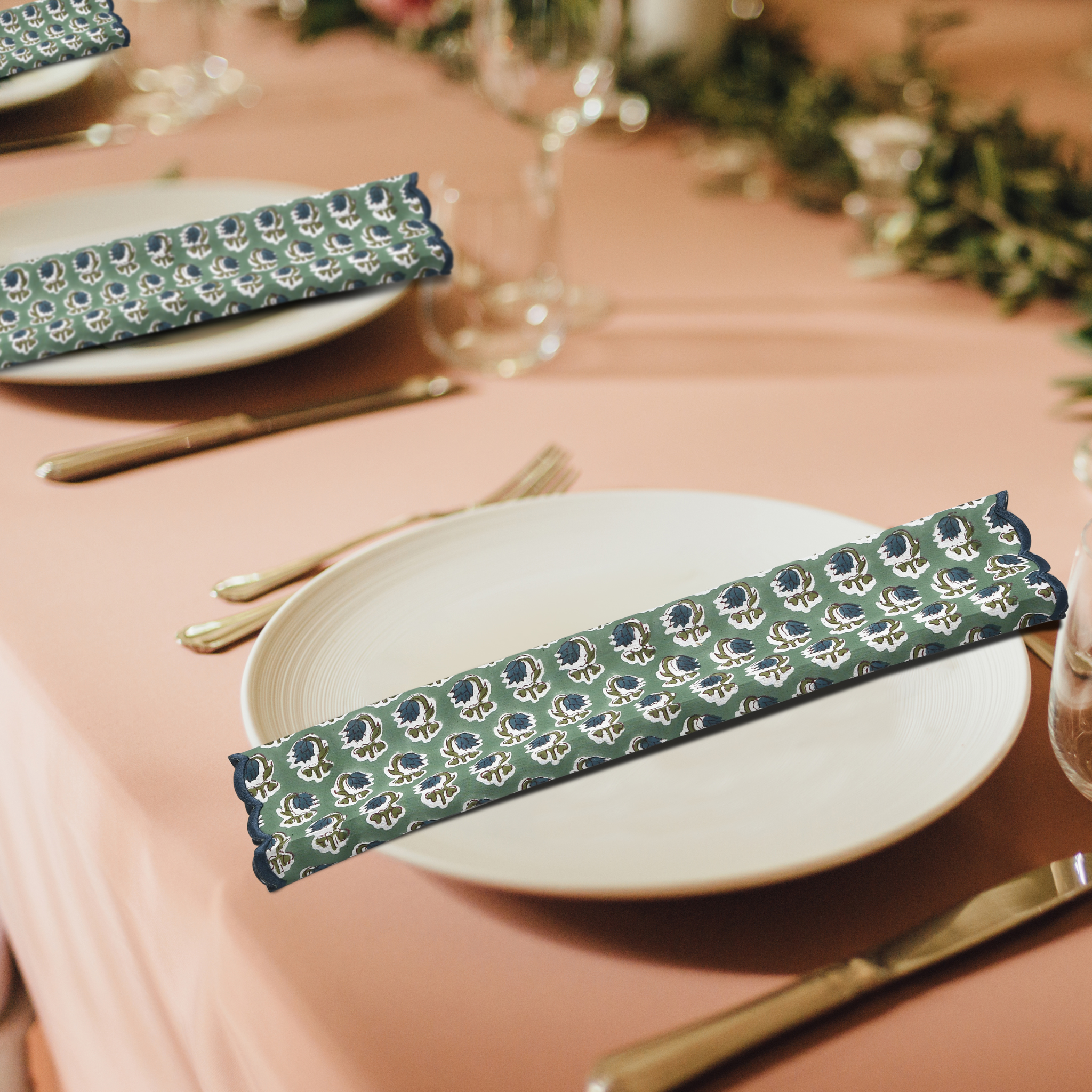 Table setting with green patterned napkins on a pink tablecloth