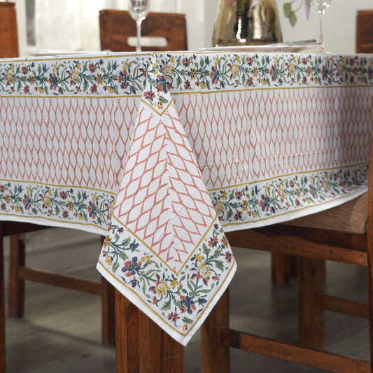 Dining table with a floral-patterned tablecloth and a vase of flowers.