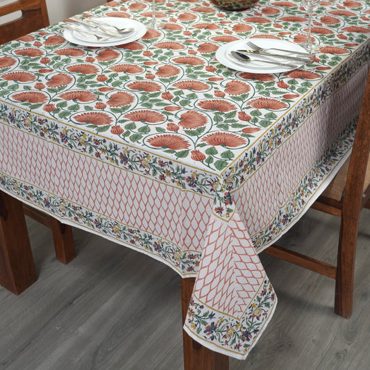 Dining table with a floral patterned tablecloth, plates, and cutlery.