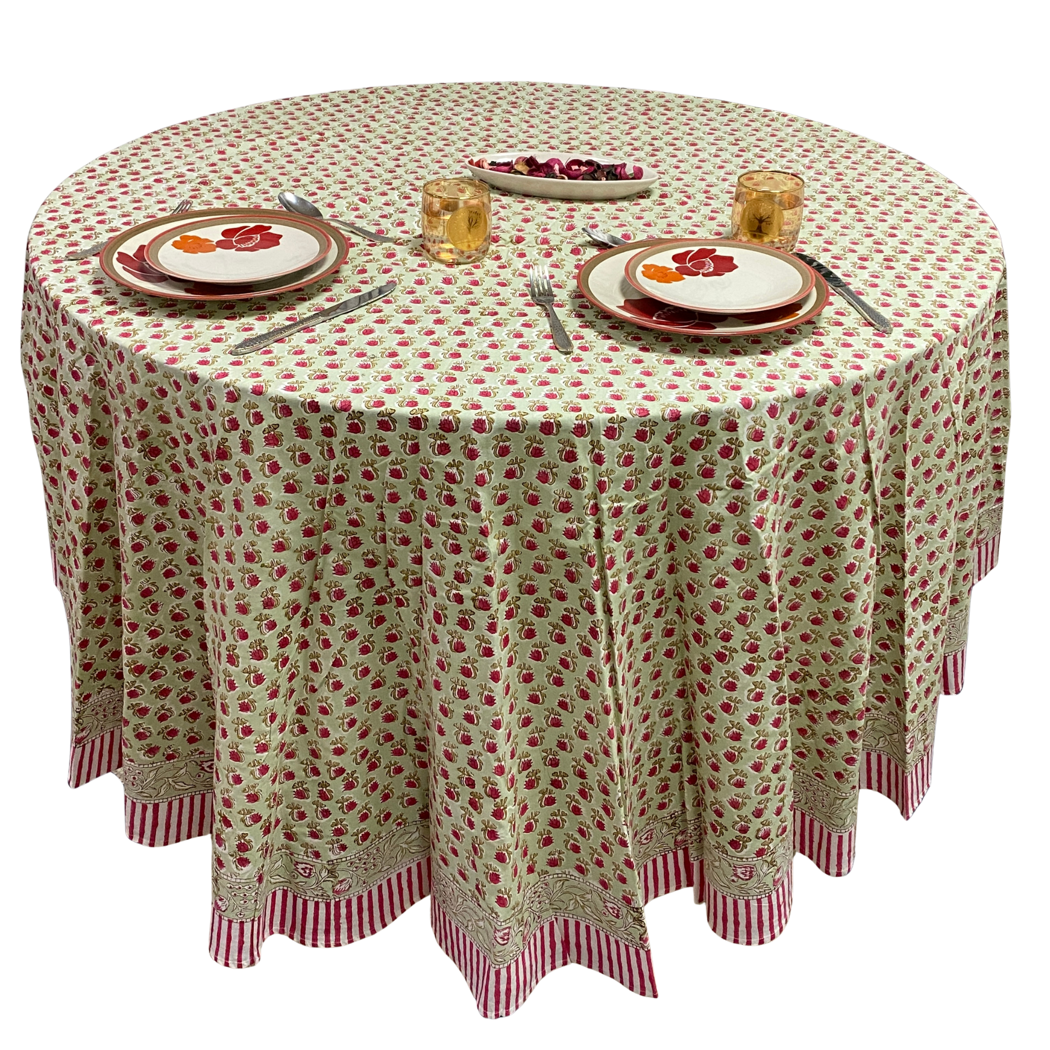 Round table with a floral tablecloth set for dinner with plates, glasses, and cutlery.