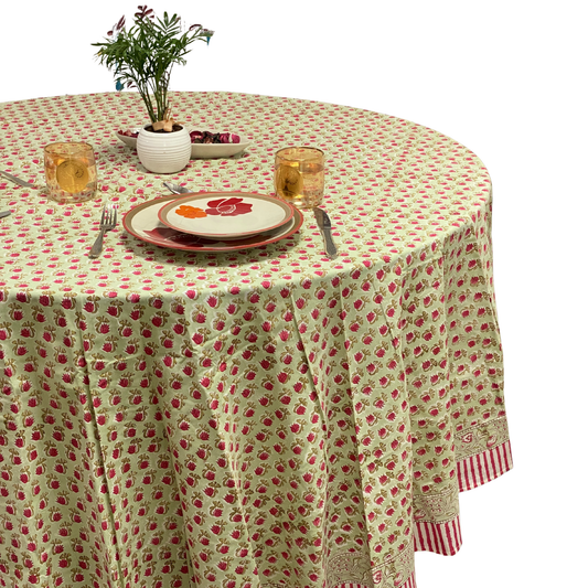 Round table with a floral tablecloth, plates, glasses, and cutlery on a white background