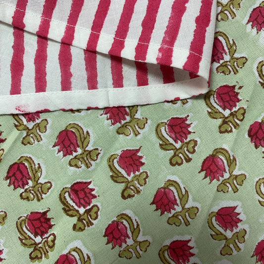 Close-up of fabric with red and white striped pattern on top and pink floral design on green background below.
