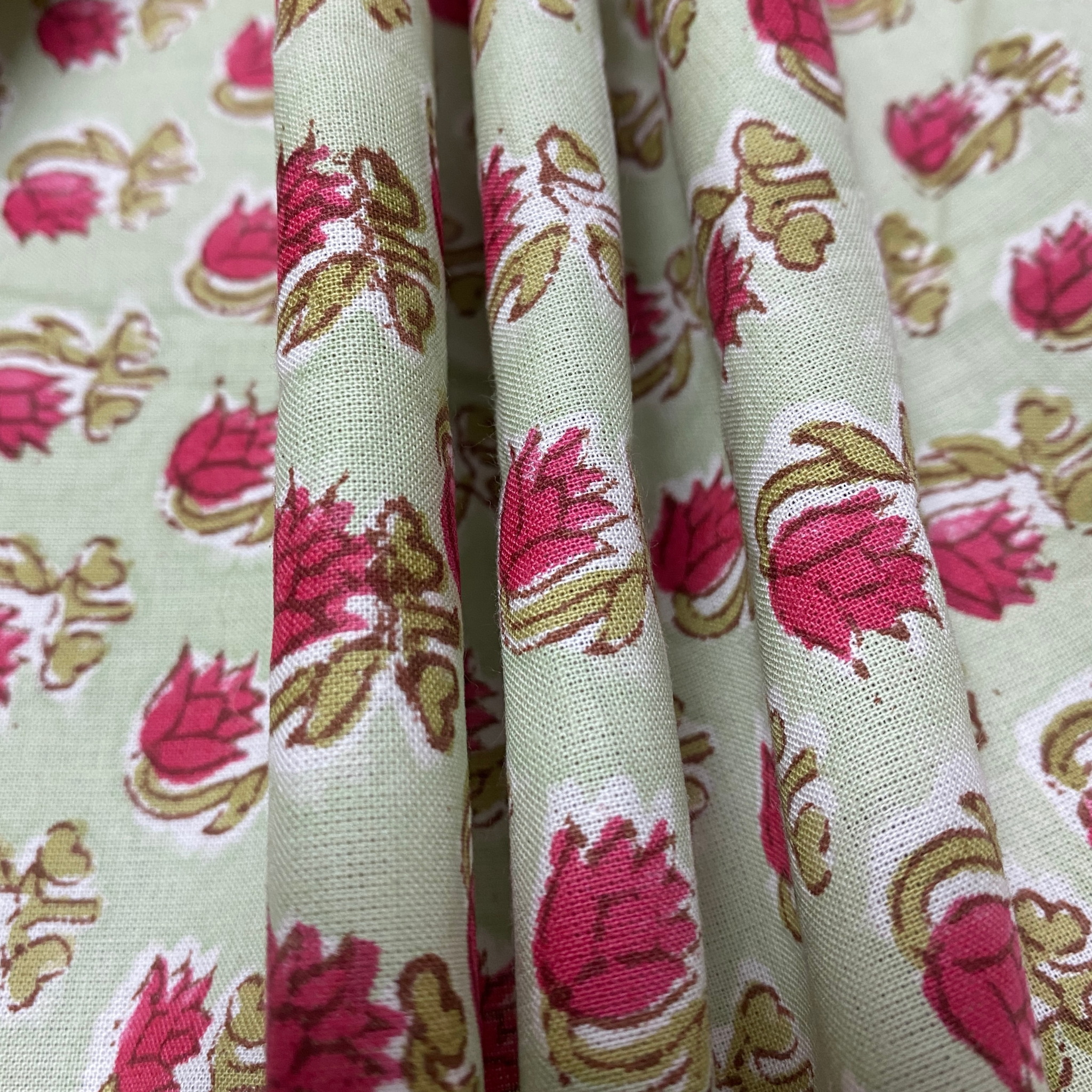 Close-up of floral fabric with pink flowers and green leaves on a light background