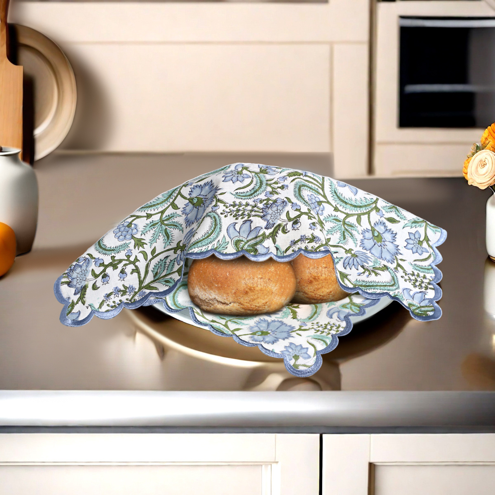Bread on a plate covered with a decorative floral cloth in a kitchen setting.