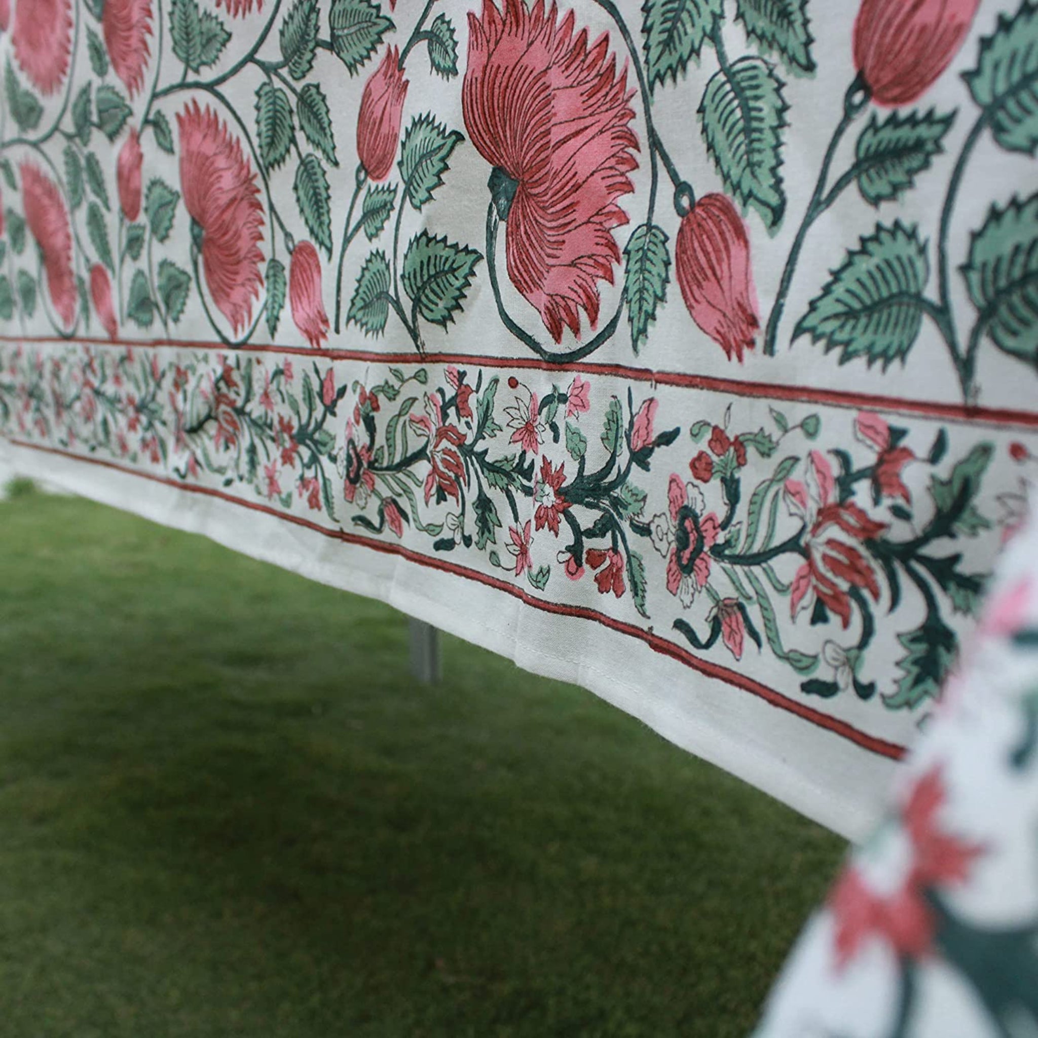 Floral patterned fabric with red and green colors on a white background.