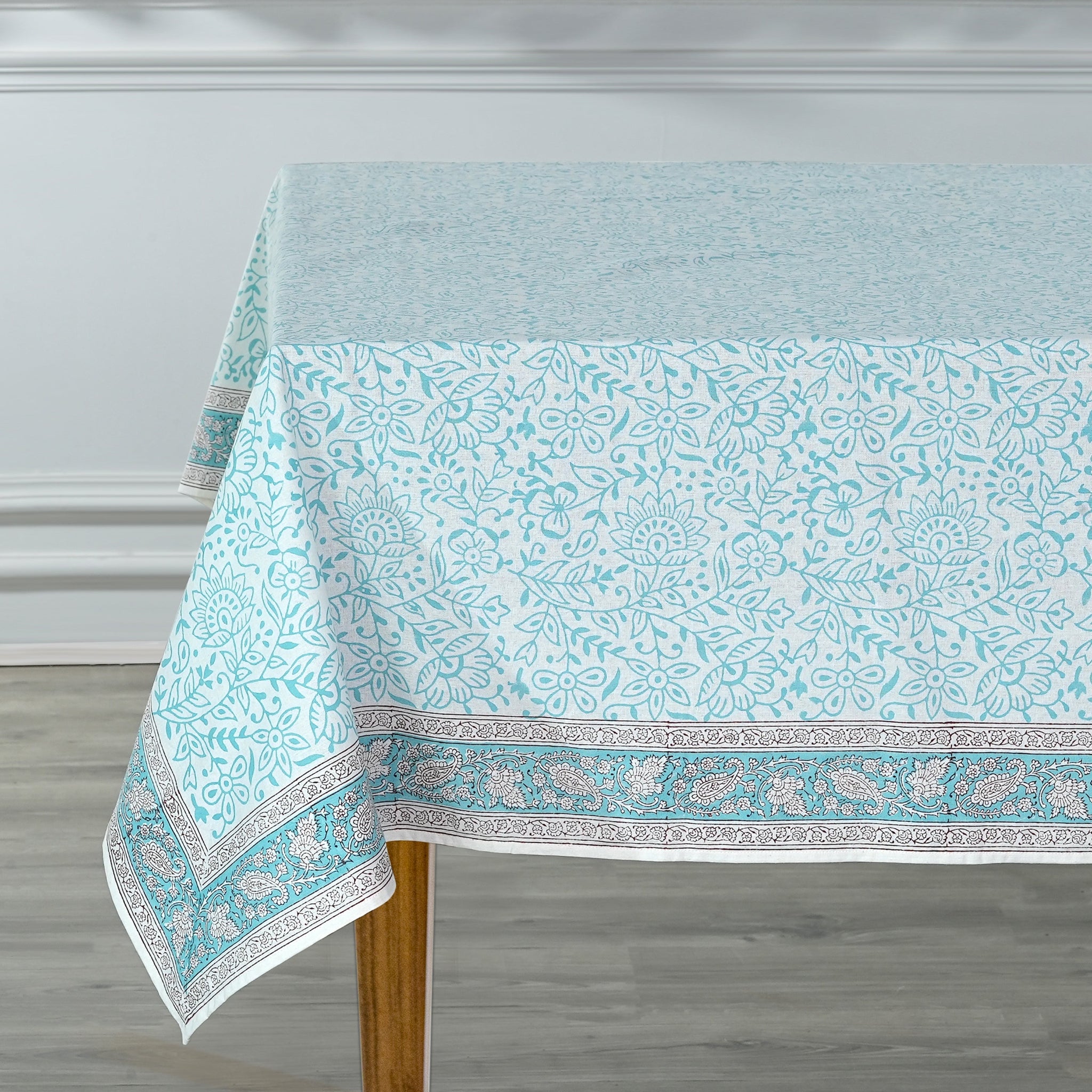 Tablecloth with a blue floral pattern on a wooden table against a white wall.