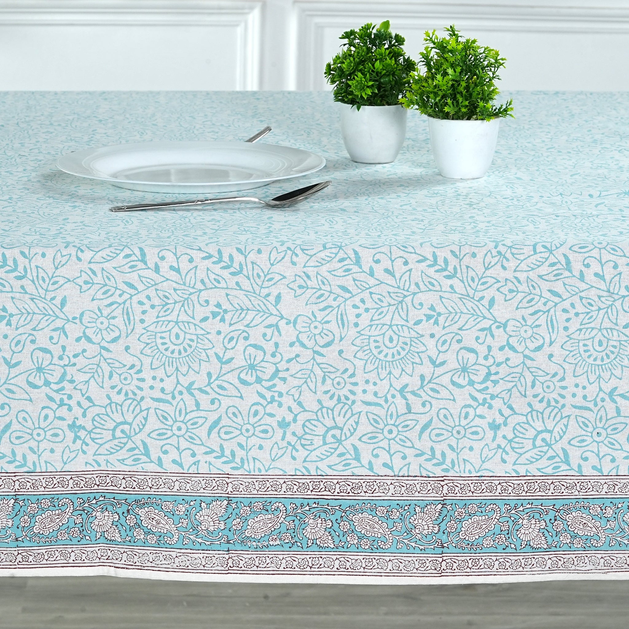 Tablecloth with floral pattern on a table setting with plates and cutlery.