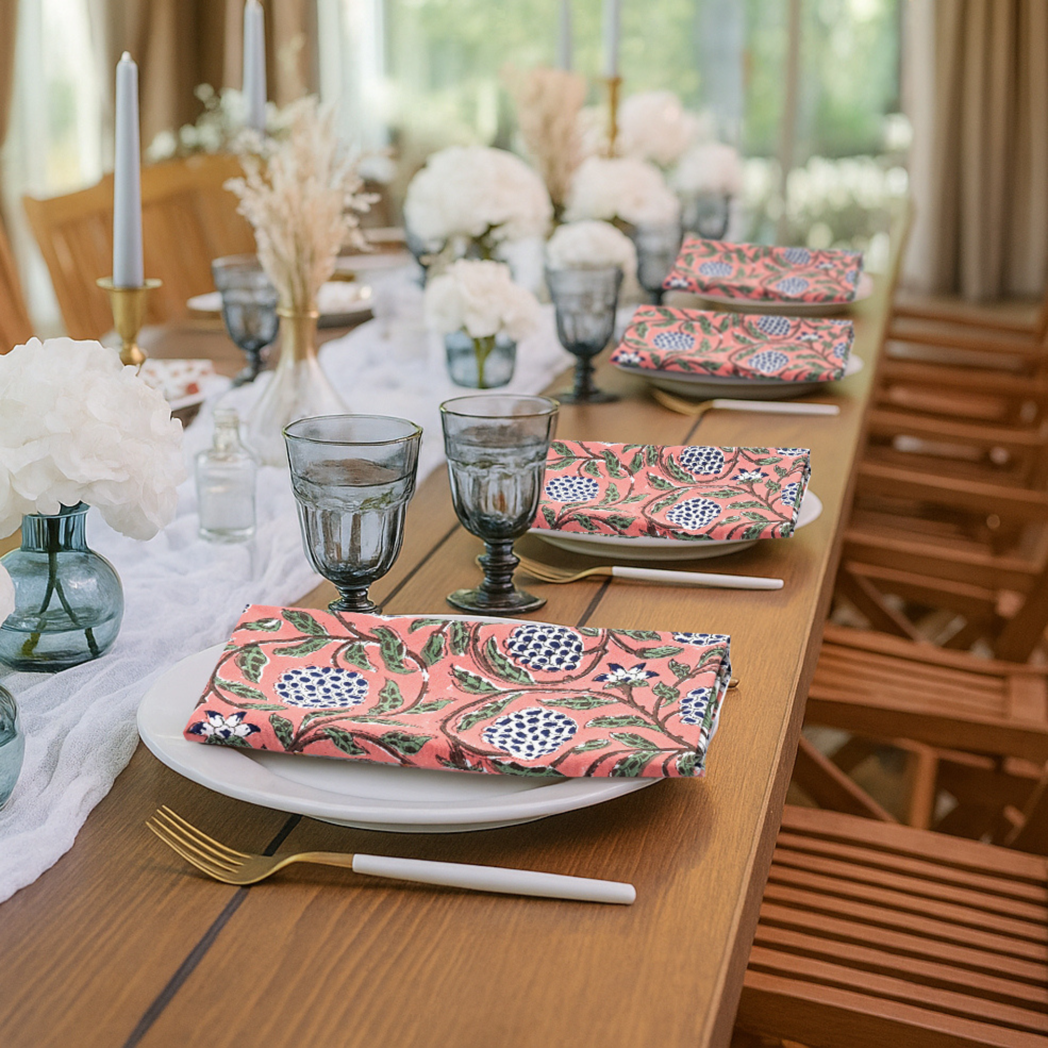 Dining table set with floral-patterned plates and glasses, surrounded by chairs and a window view.