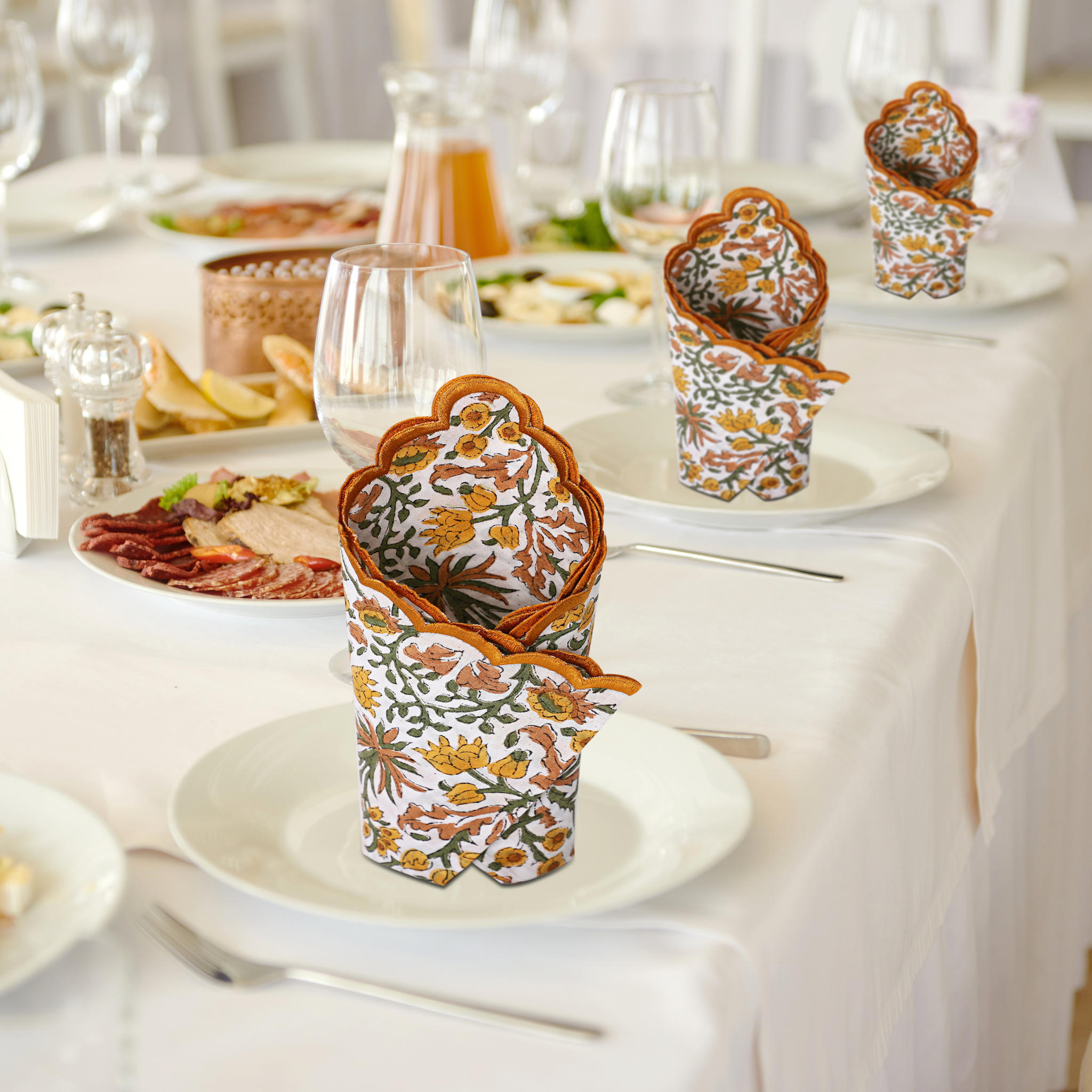 Decorative paper cups with floral patterns on a table setting with plates and glasses.