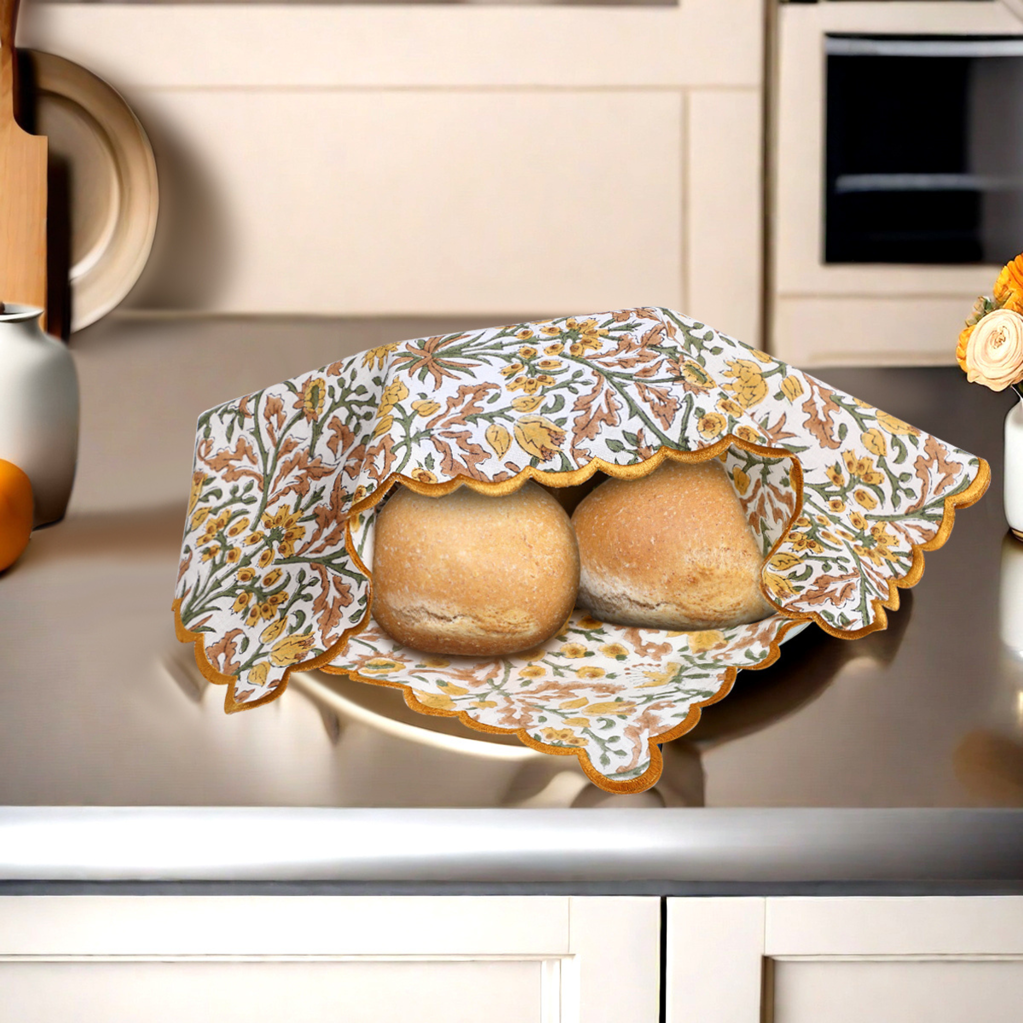 Two loaves of bread in a decorative floral bread cover on a kitchen counter.
