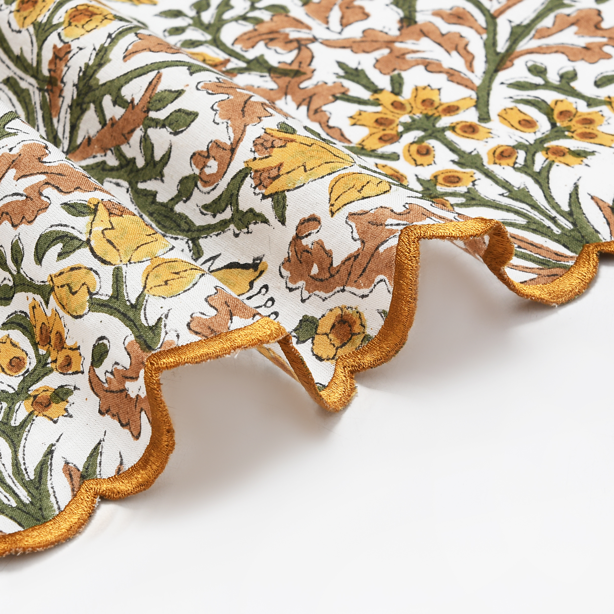 Decorative pillow with floral pattern and gold trim on a white background