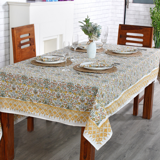 Dining table set with a floral tablecloth, plates, and glasses in a kitchen.