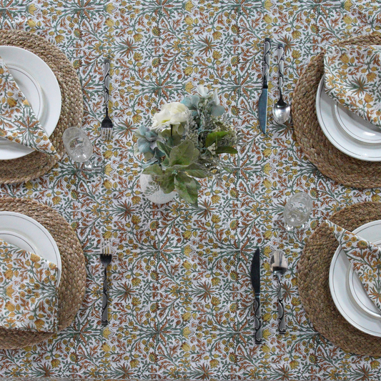 Patterned tablecloth with plates, cutlery, and a floral centerpiece.