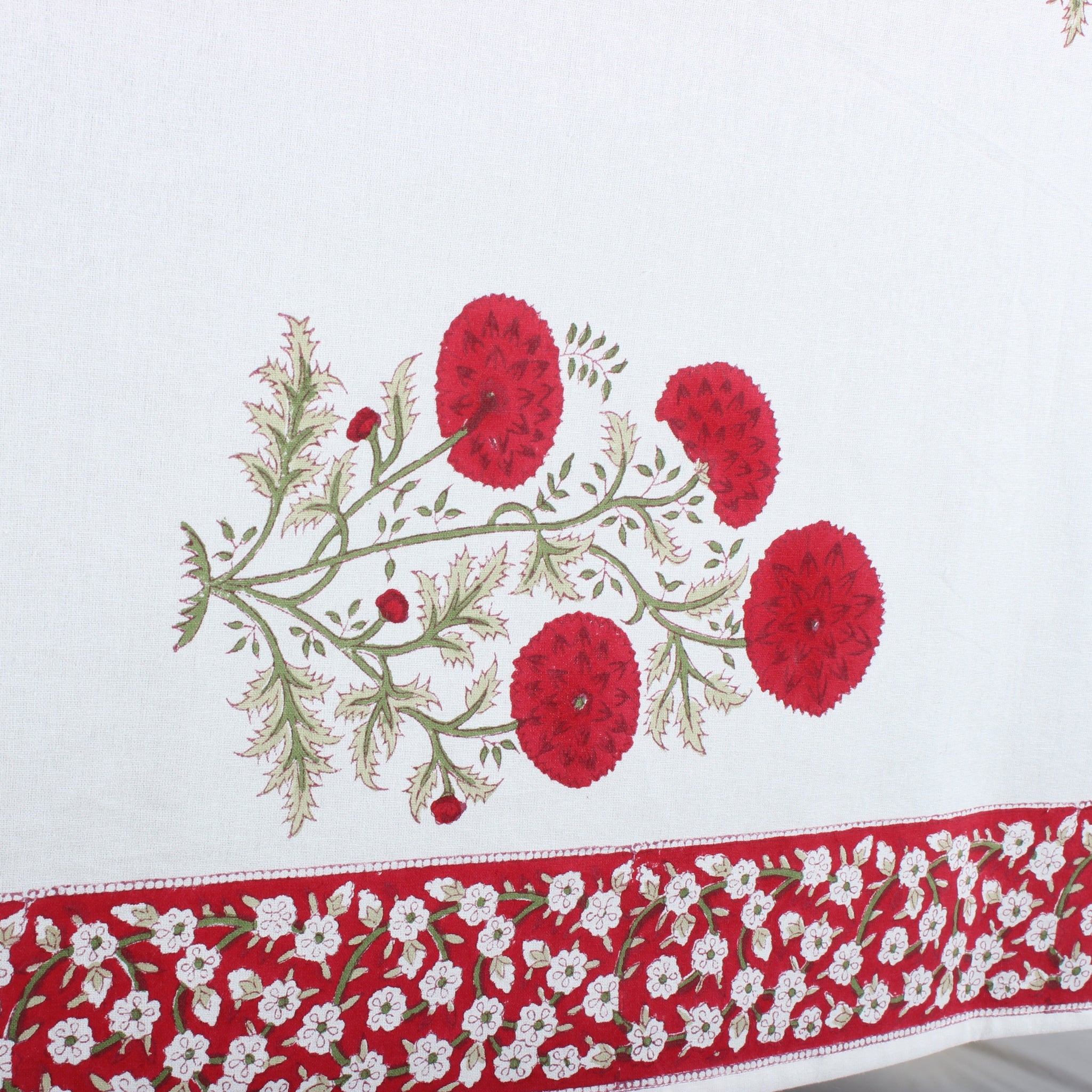 Embroidered tablecloth with red floral design on a white background