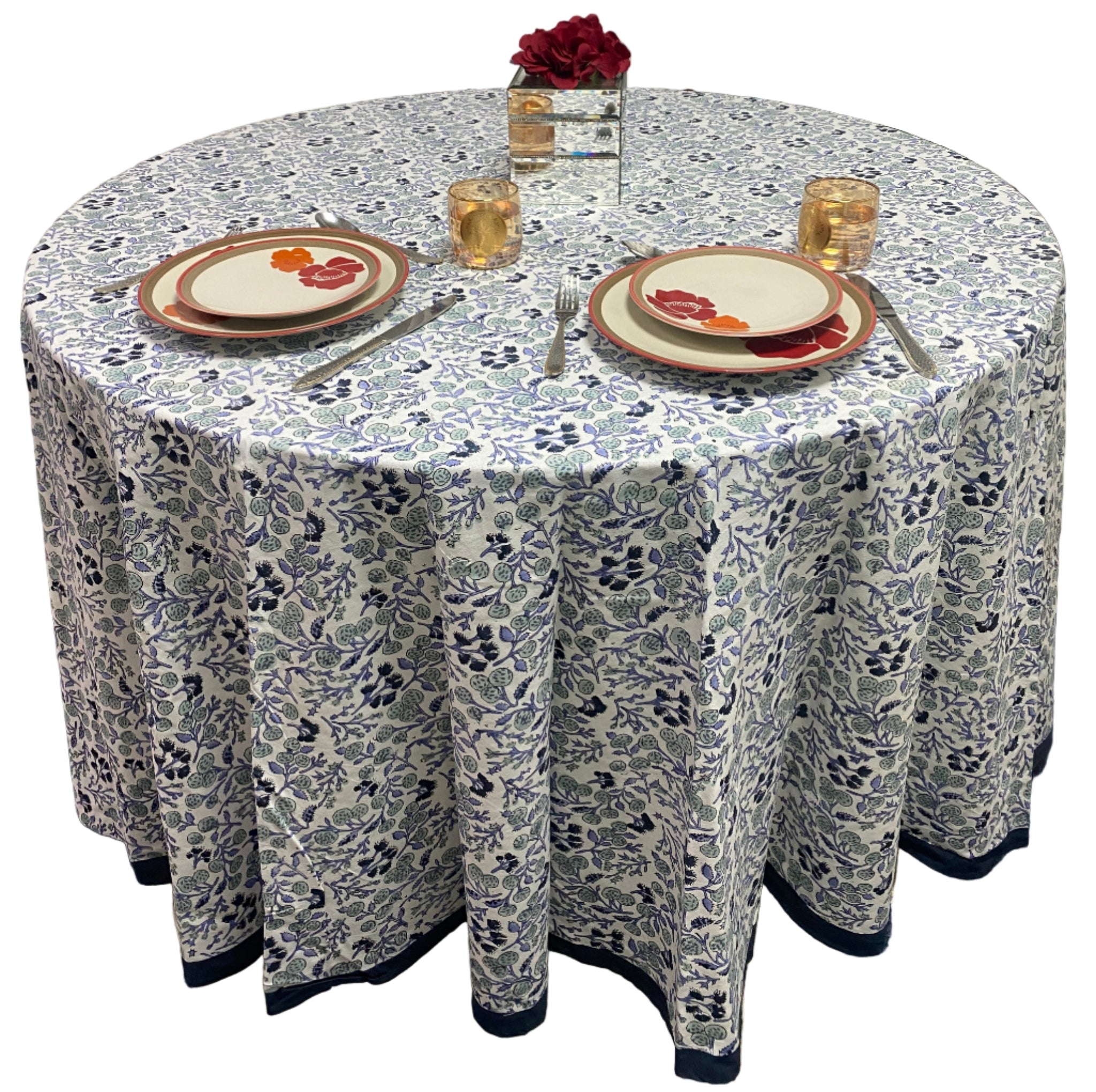Round table with floral patterned tablecloth, plates, and cutlery.