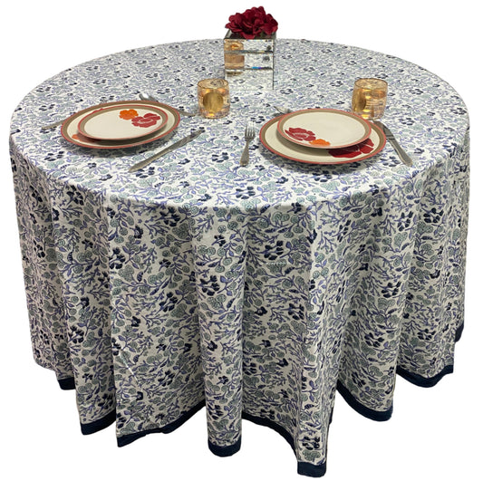 Round table with floral patterned tablecloth, plates, and cutlery.