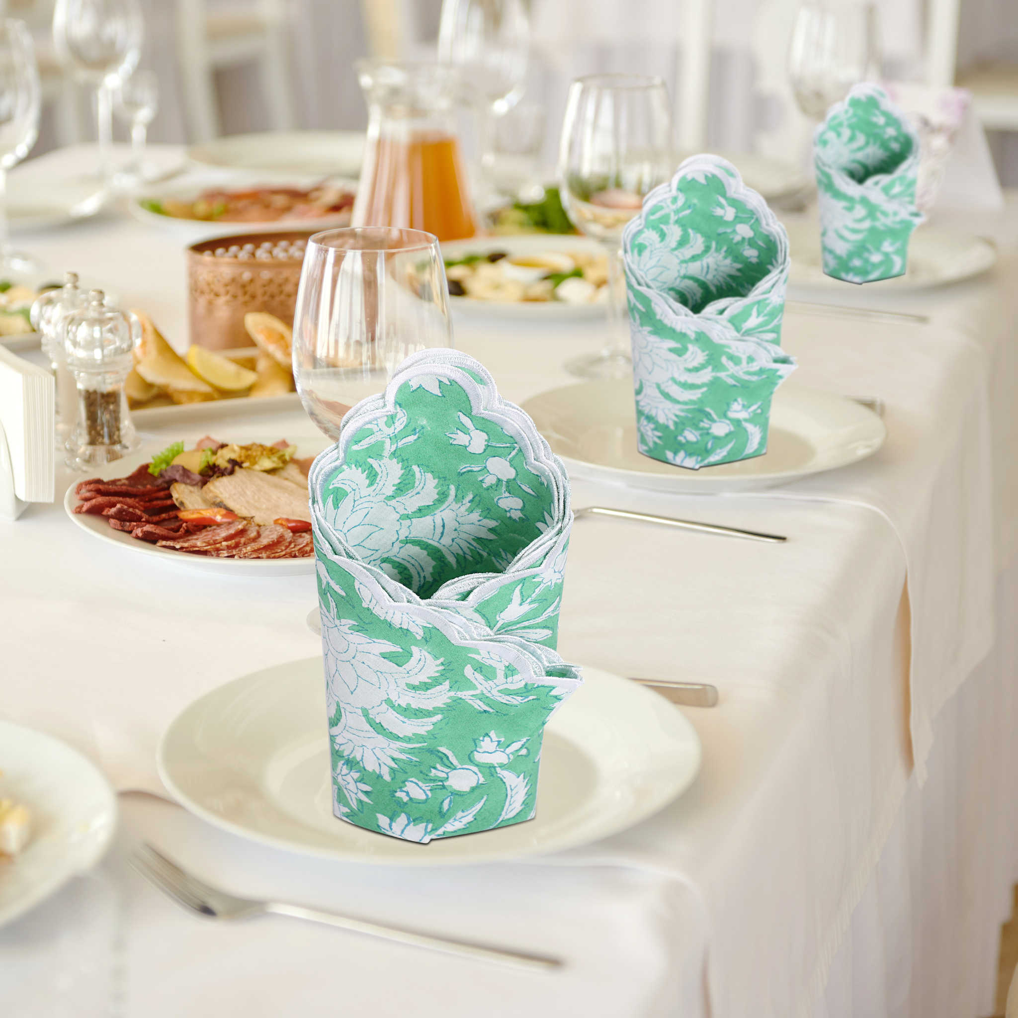 Green and white patterned napkin holders on a table with plates and glasses.