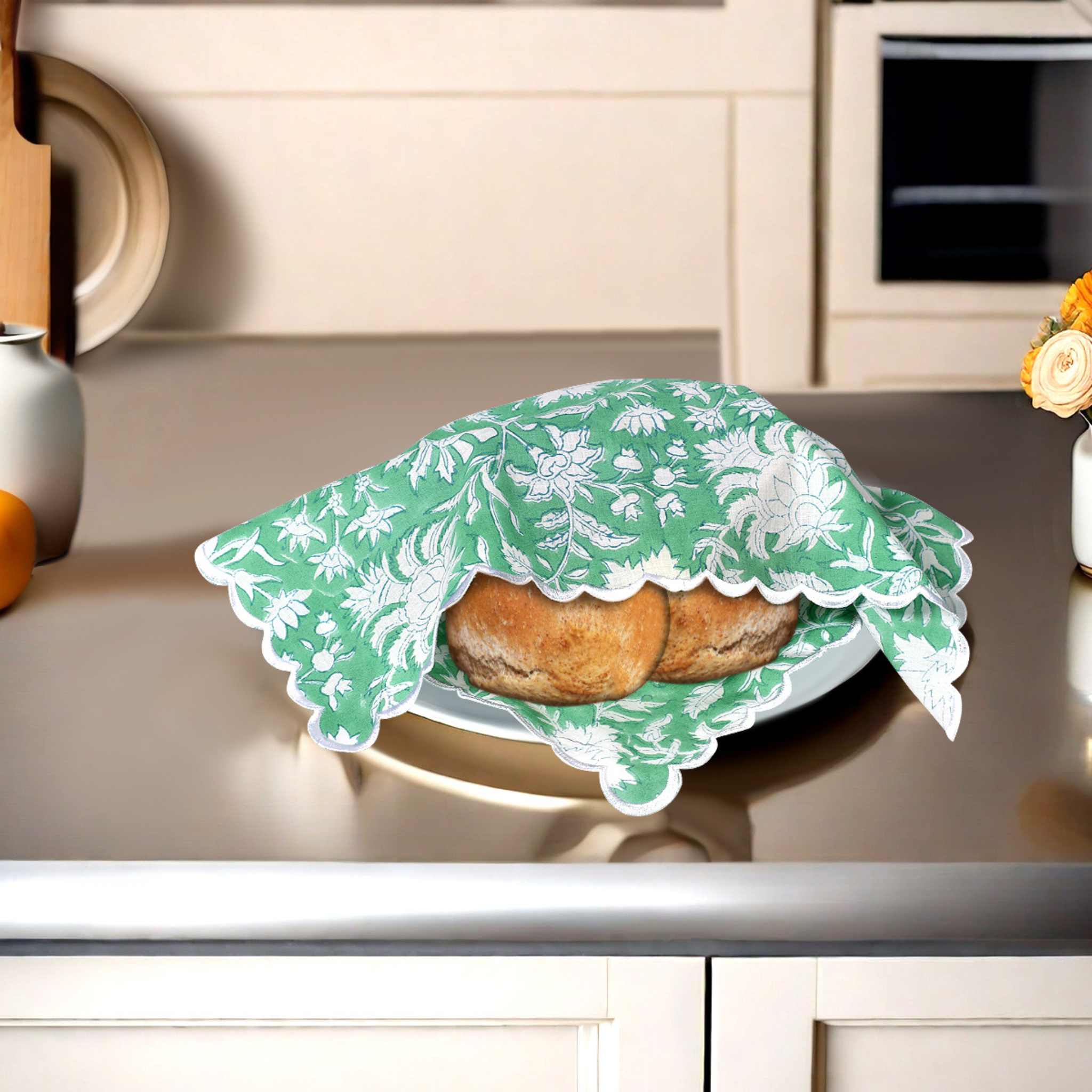 Two pastries under a green floral lace cover on a kitchen counter.