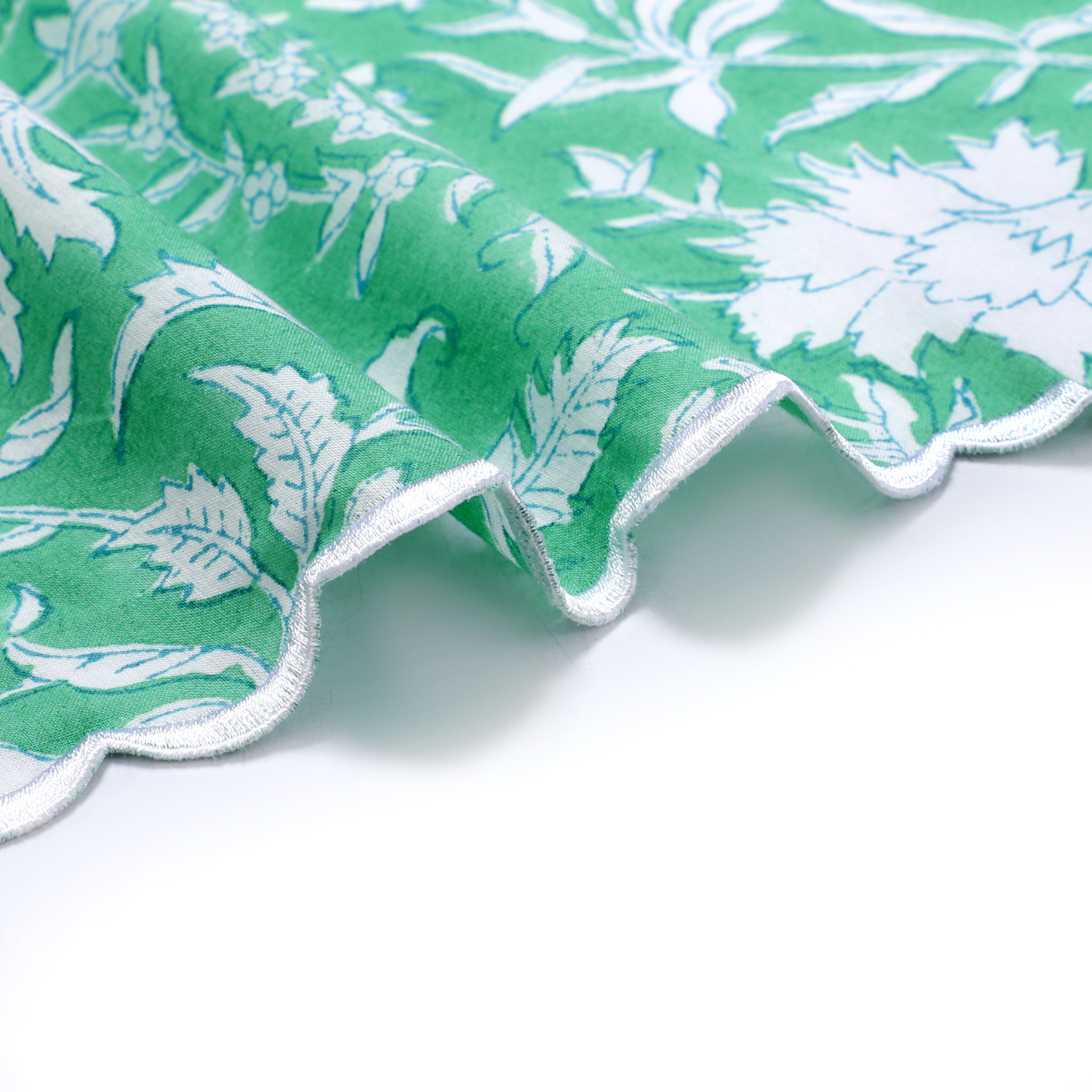 Green fabric with white floral pattern on a white background