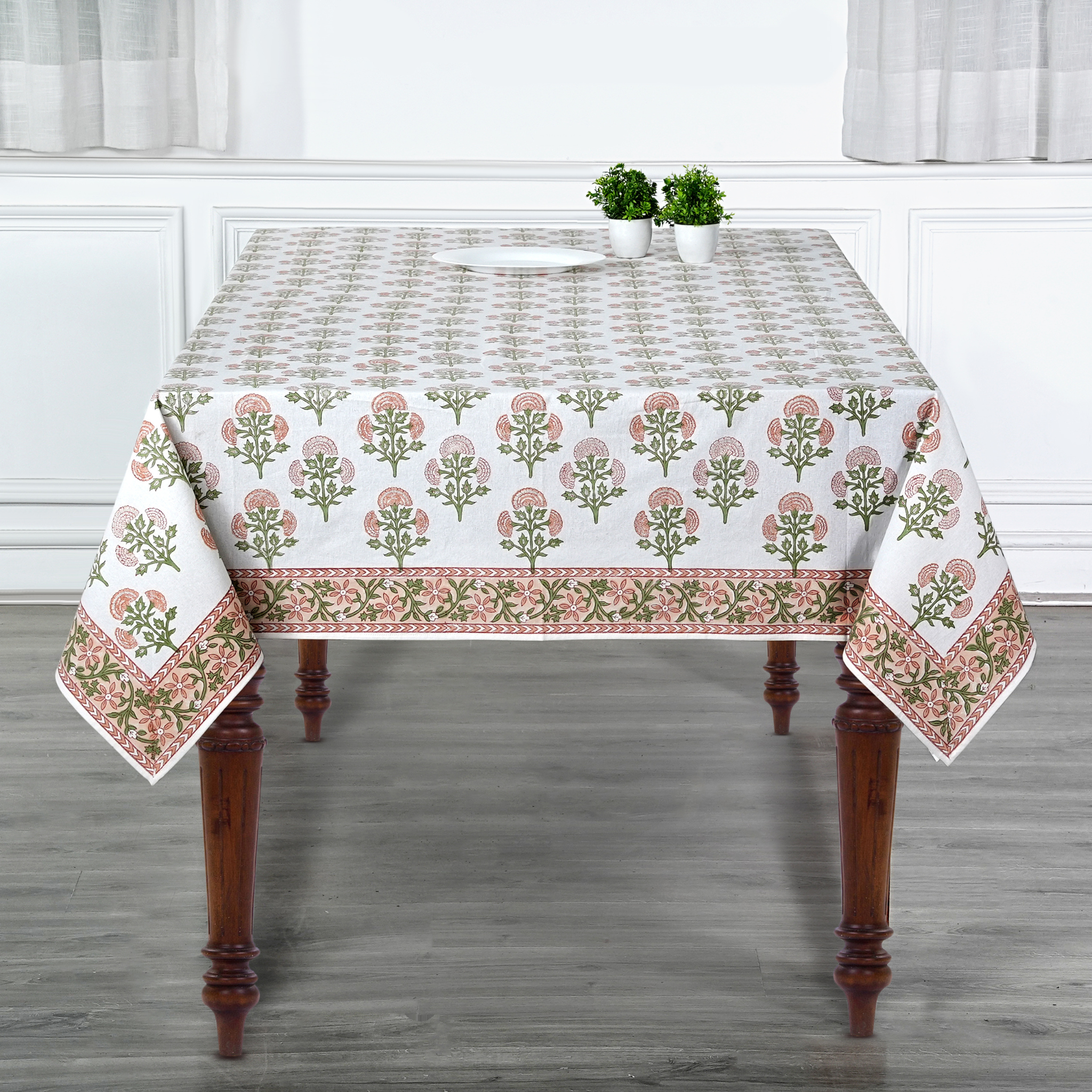 Decorative tablecloth with floral pattern on a wooden table in a room.