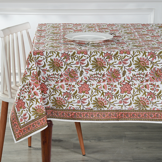 Floral patterned tablecloth on a wooden table with a white chair.