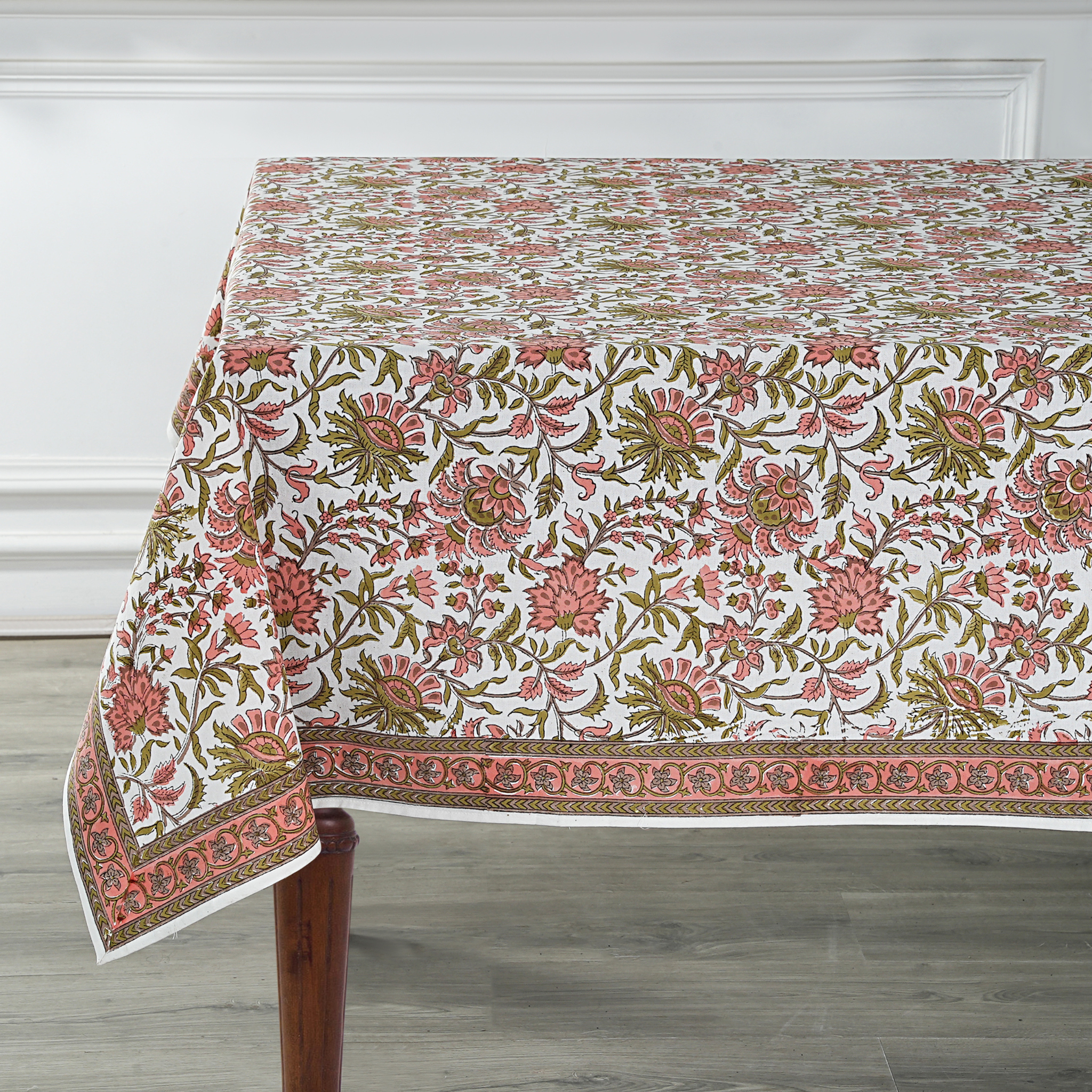 Floral patterned tablecloth on a wooden table with a white wall background