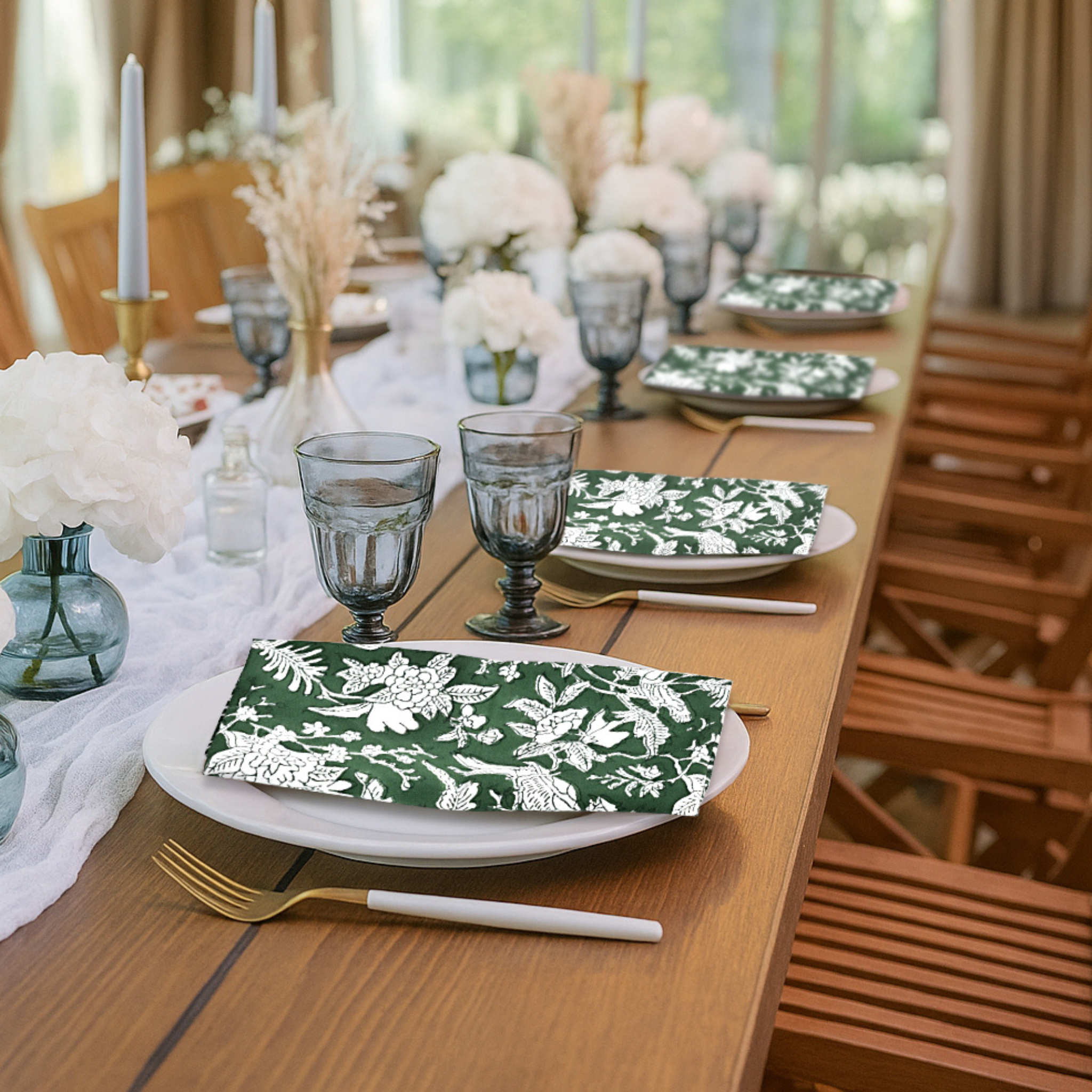 Elegant table setting with green floral napkins, white flowers, and glassware.