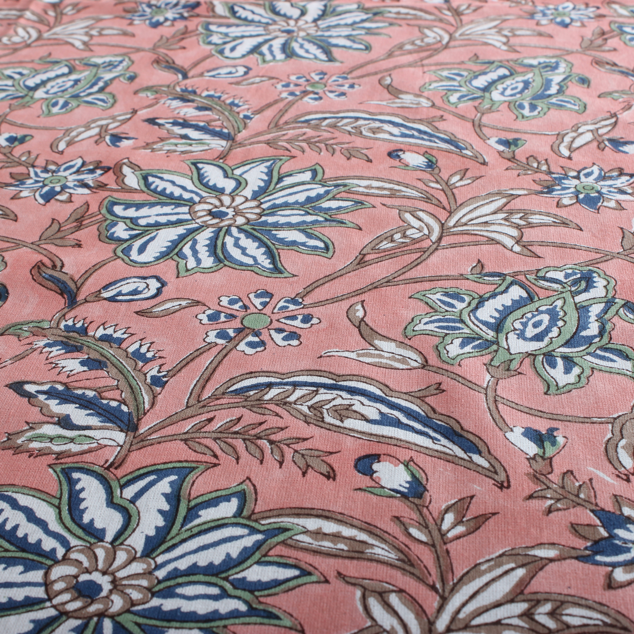 Floral patterned fabric with blue and green flowers on a pink background
