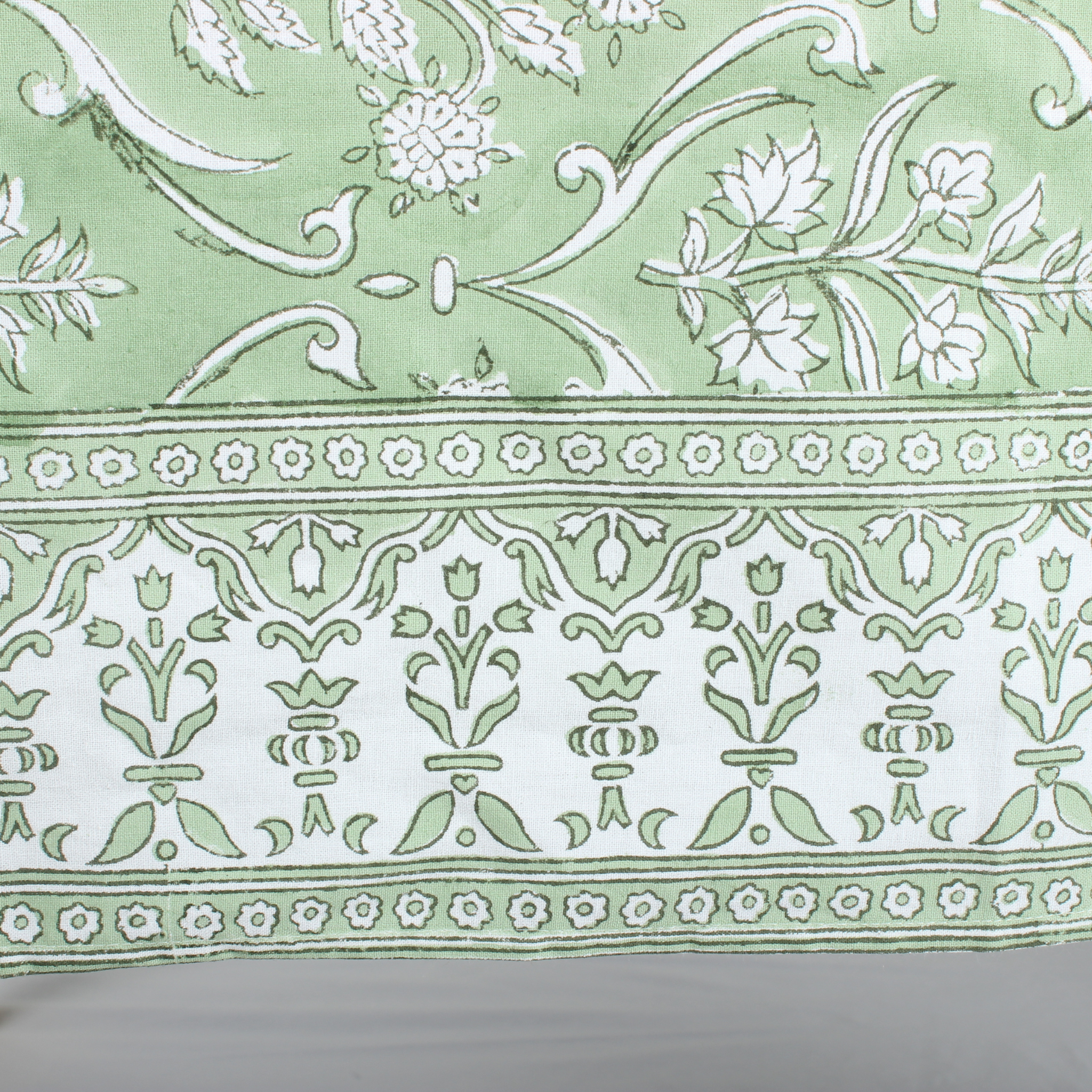 Decorative fabric with intricate white patterns on a green background