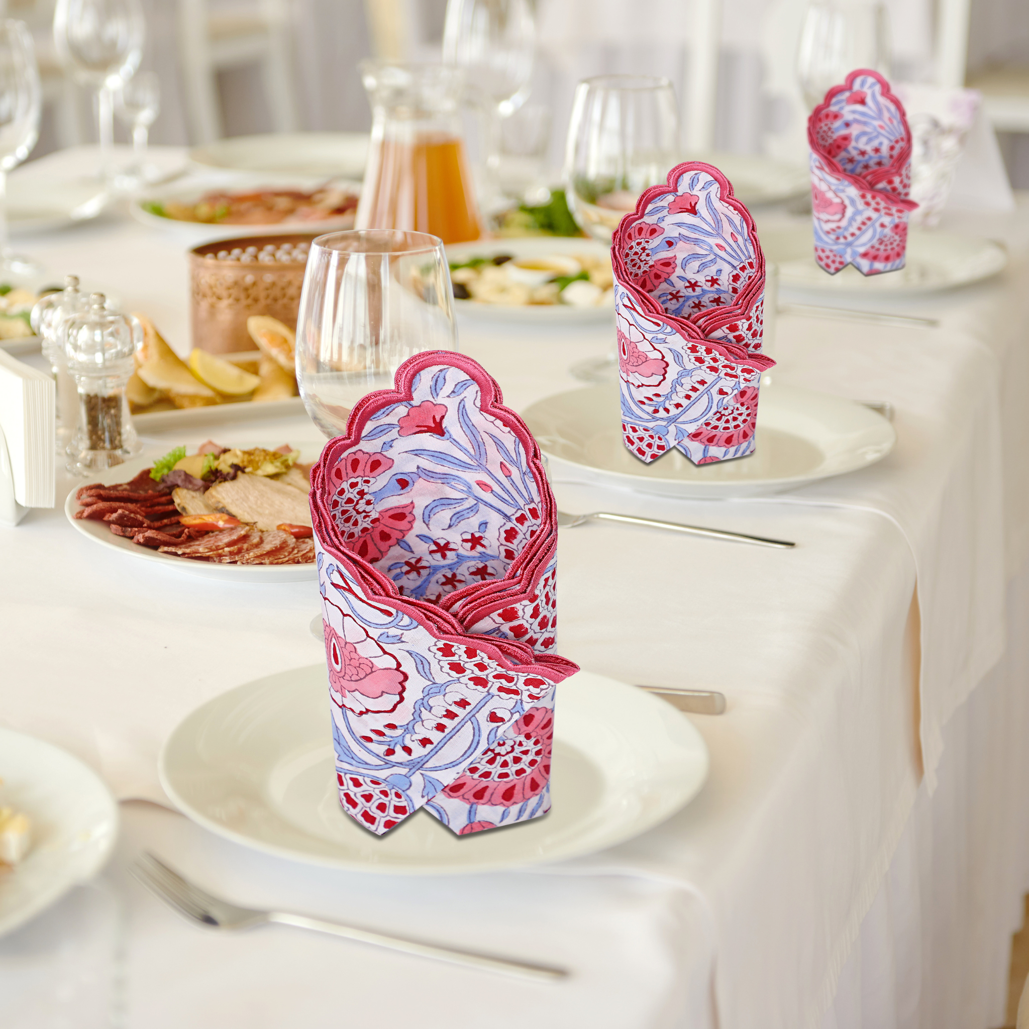 Decorative pink and blue napkin holders on a table setting with plates and glasses.