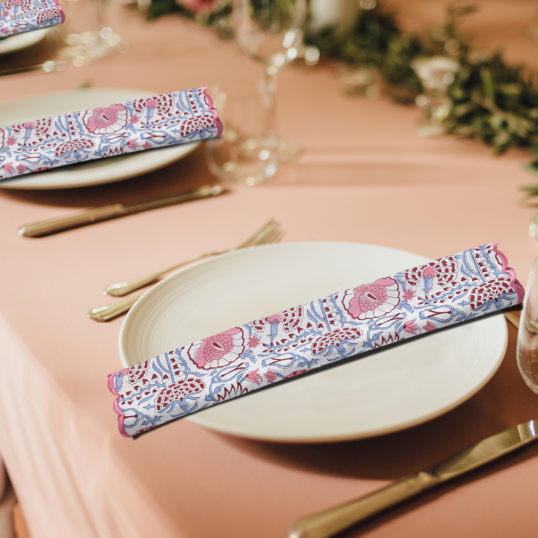 Table setting with floral-patterned napkins on plates, cutlery, and glasses.