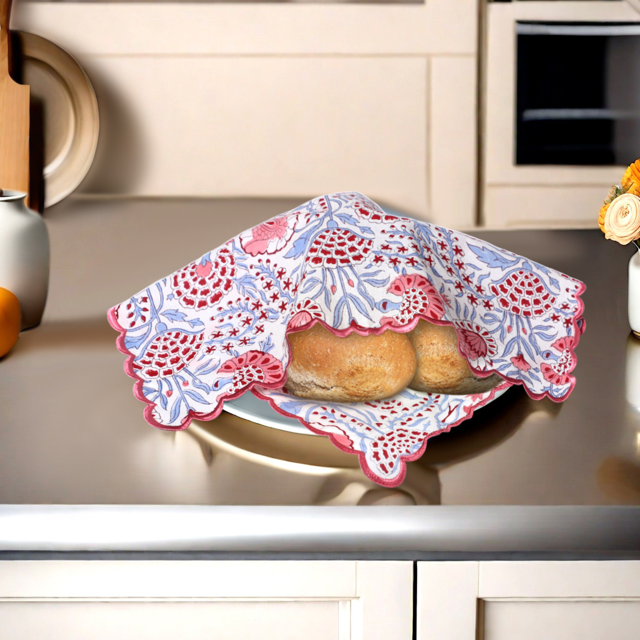 Baked goods in a decorative pink and blue cloth on a kitchen counter.