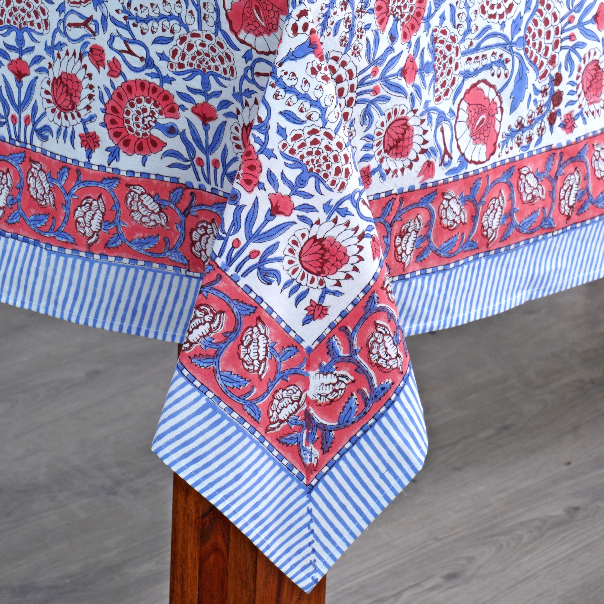 Decorative tablecloth with red, blue, and white floral patterns on a wooden surface.