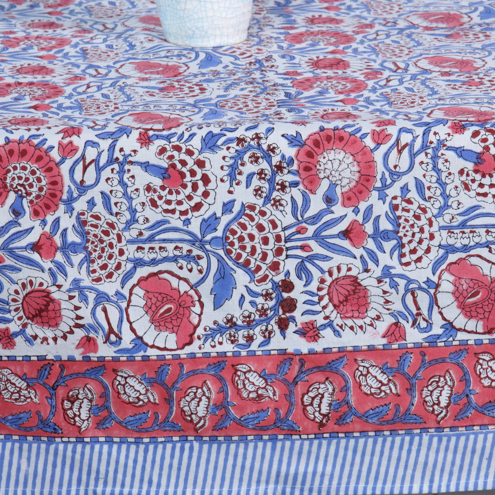 Floral patterned tablecloth with red, blue, and white colors on a striped background.