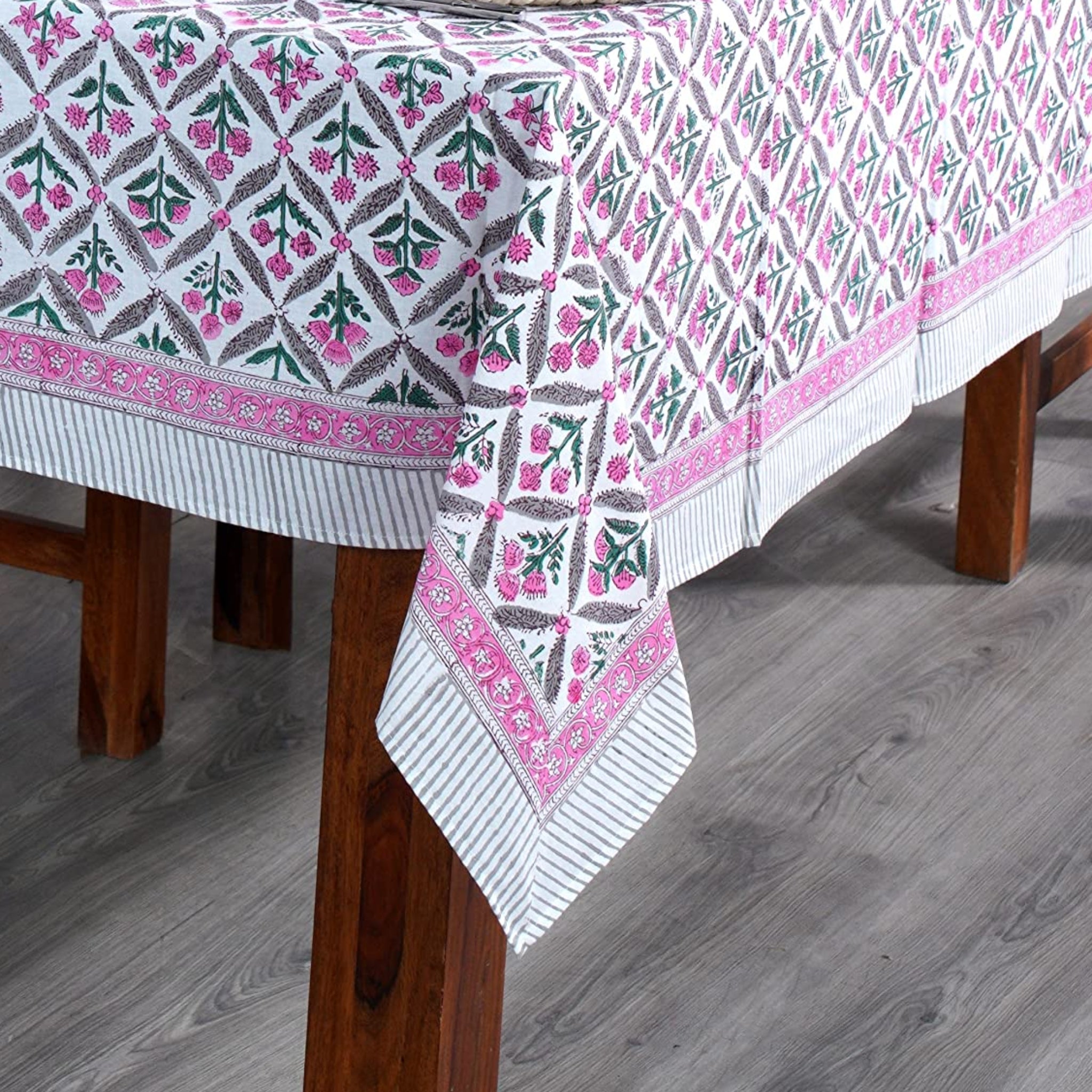Dining table set with a patterned tablecloth, wooden chairs, and decorative elements.