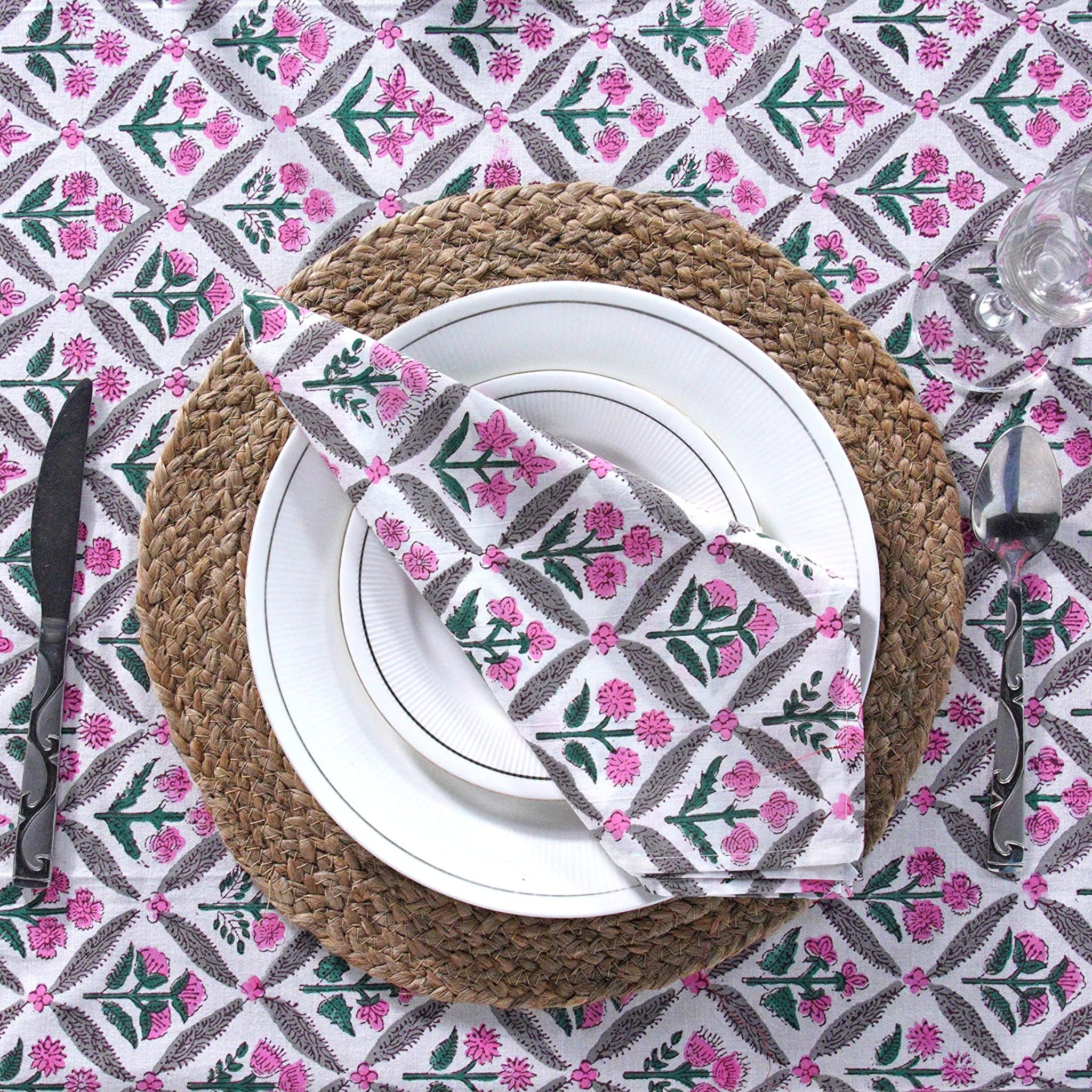 Table setting with floral patterned tablecloth, plate, napkin, and cutlery.