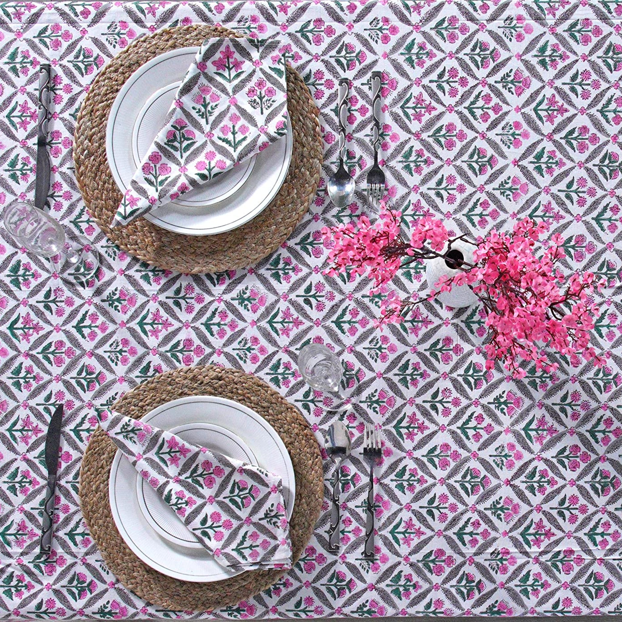 Table setting with plates, cutlery, and napkins on a patterned tablecloth.