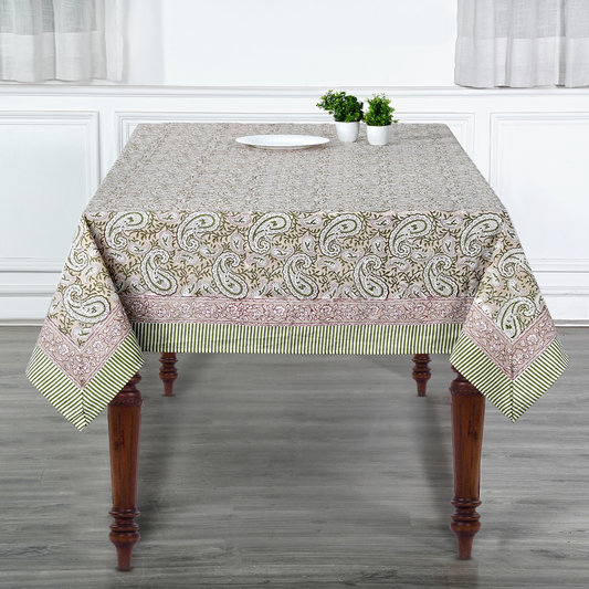 Tablecloth with paisley pattern on a wooden table in a room with white walls and gray floor.