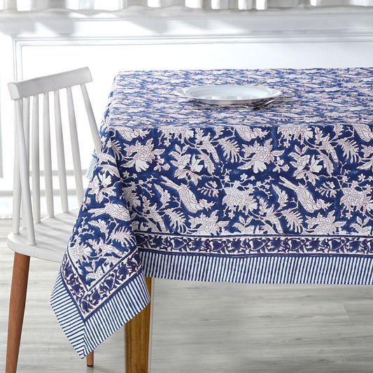 Blue and white patterned tablecloth on a wooden table with a white chair.