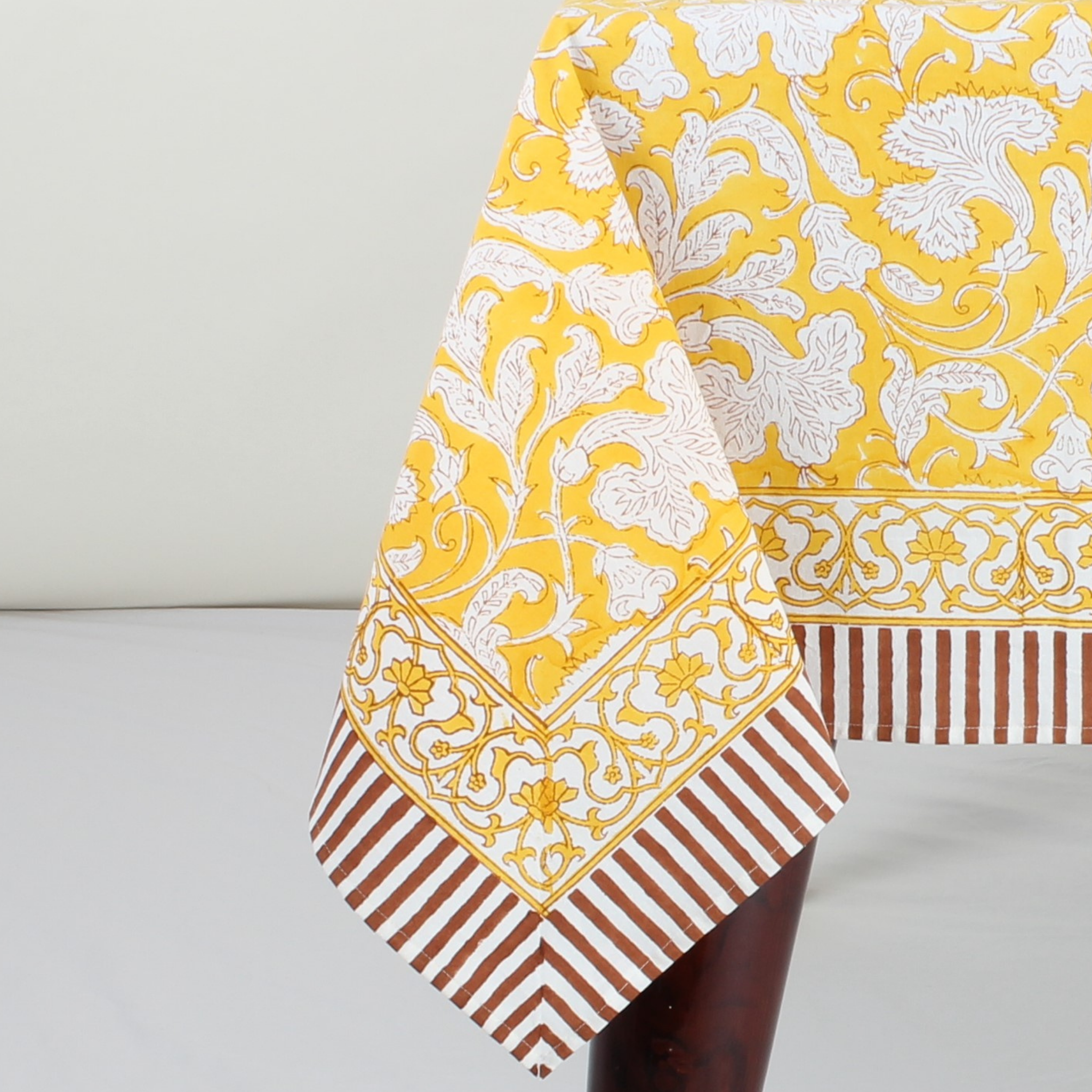 Yellow and white floral patterned fabric with brown and white striped fabric on a gray background