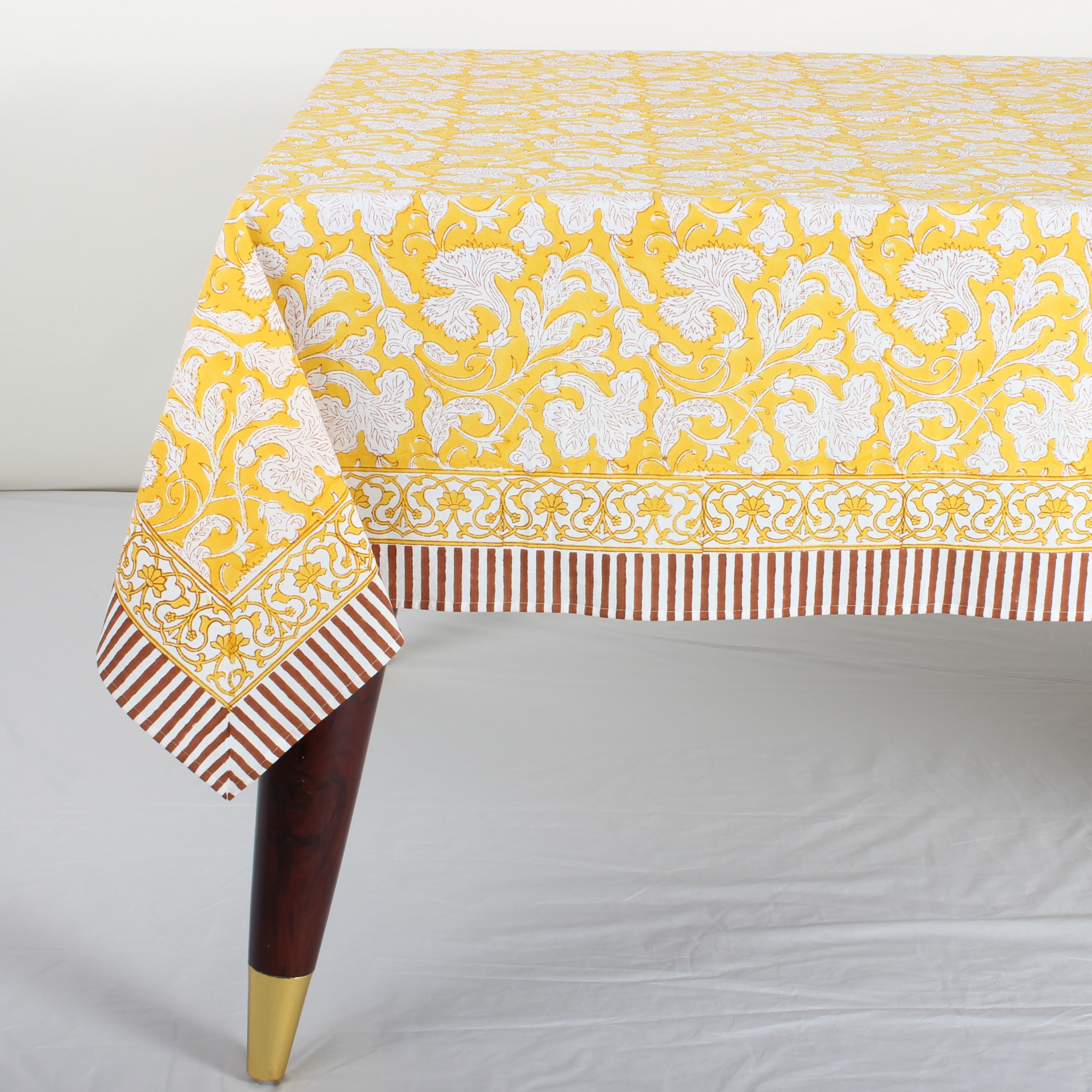 Yellow and white patterned tablecloth on a wooden table with a white background